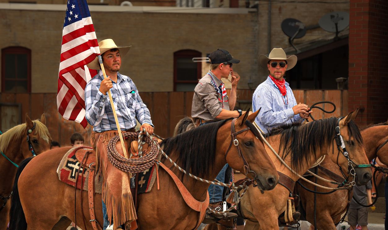 Cowboys parade with horses and American flag on a sunny day outdoors