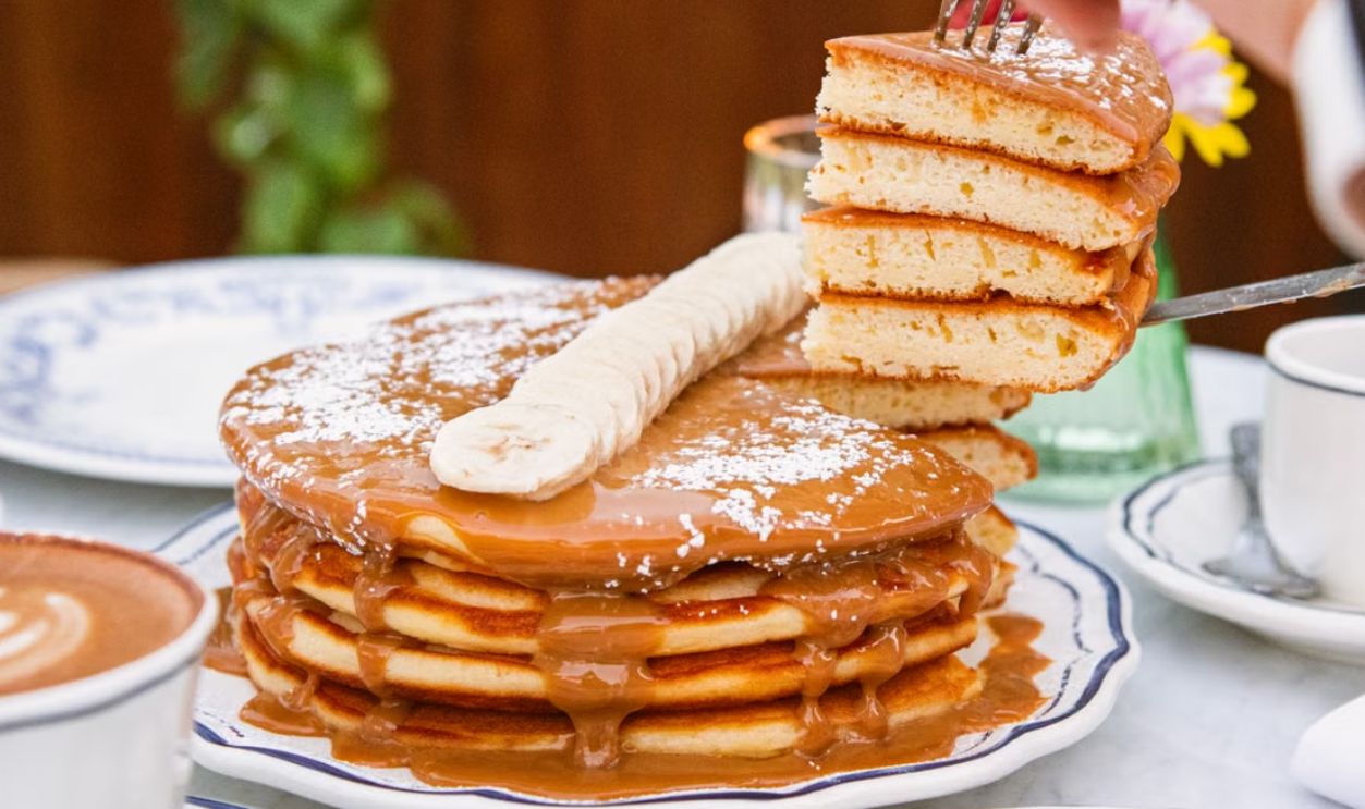 Delicious stack of pancakes topped with caramel and banana, perfect for brunch or breakfast