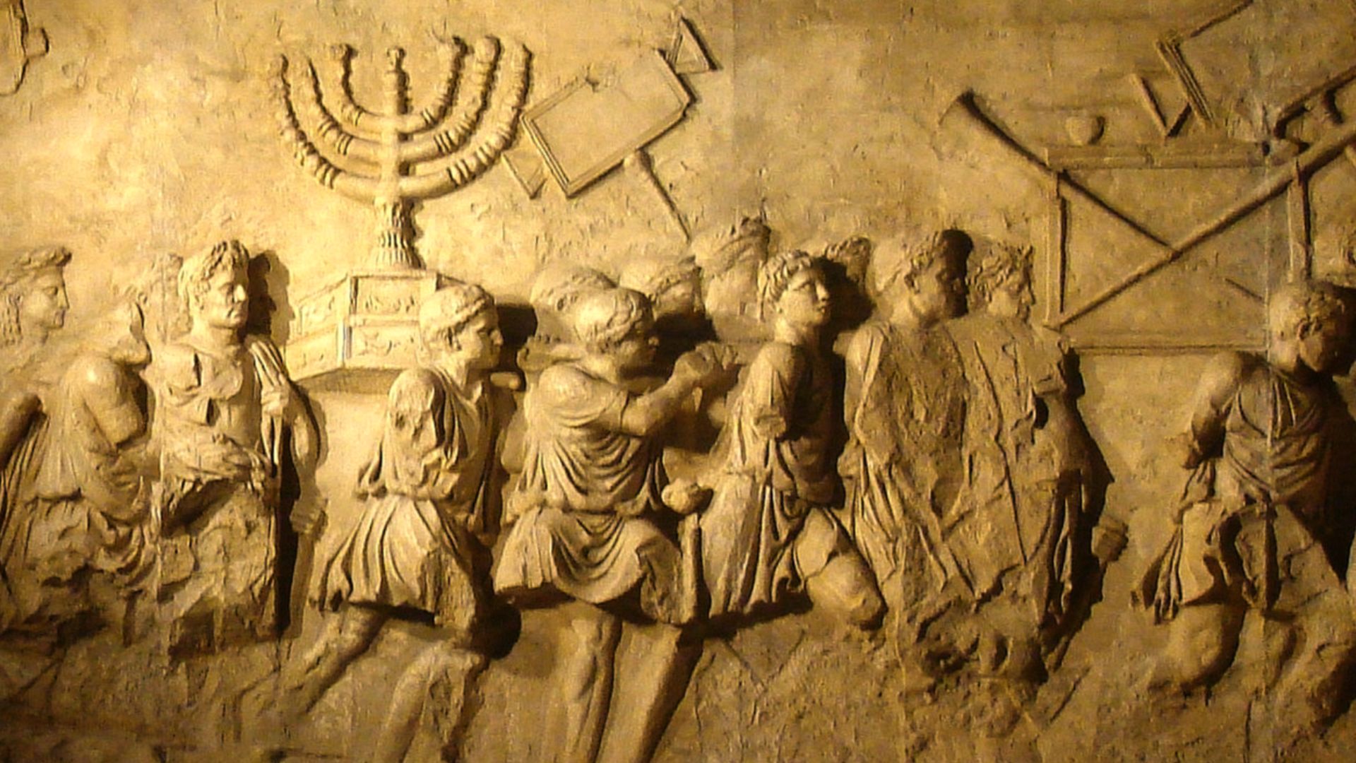 This photograph shows a modern replica of the Arch of Titus relief depicting the spoils of the Jerusalem Temple, including the temple menorah, carried in a triumphal procession through Rome following the Roman conquest of Jerusalem in 70 CE. The replica w
