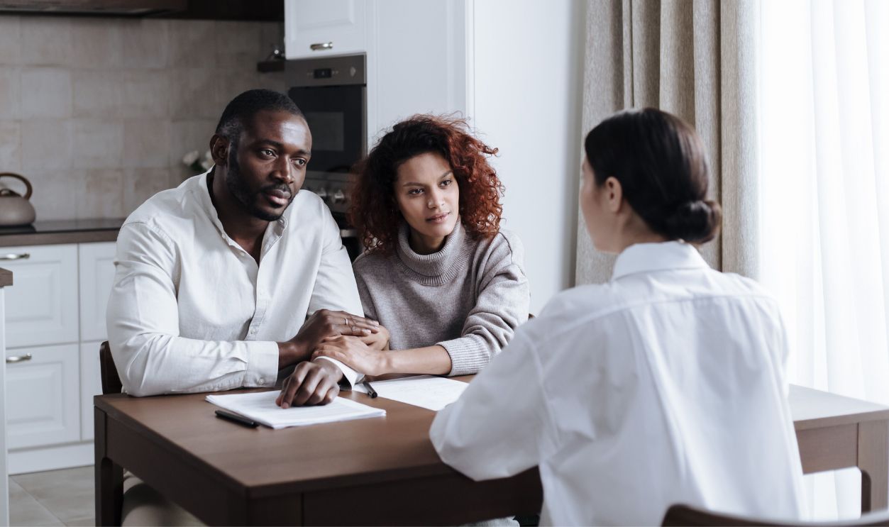 A couple discusses adoption with a social worker in a modern kitchen 