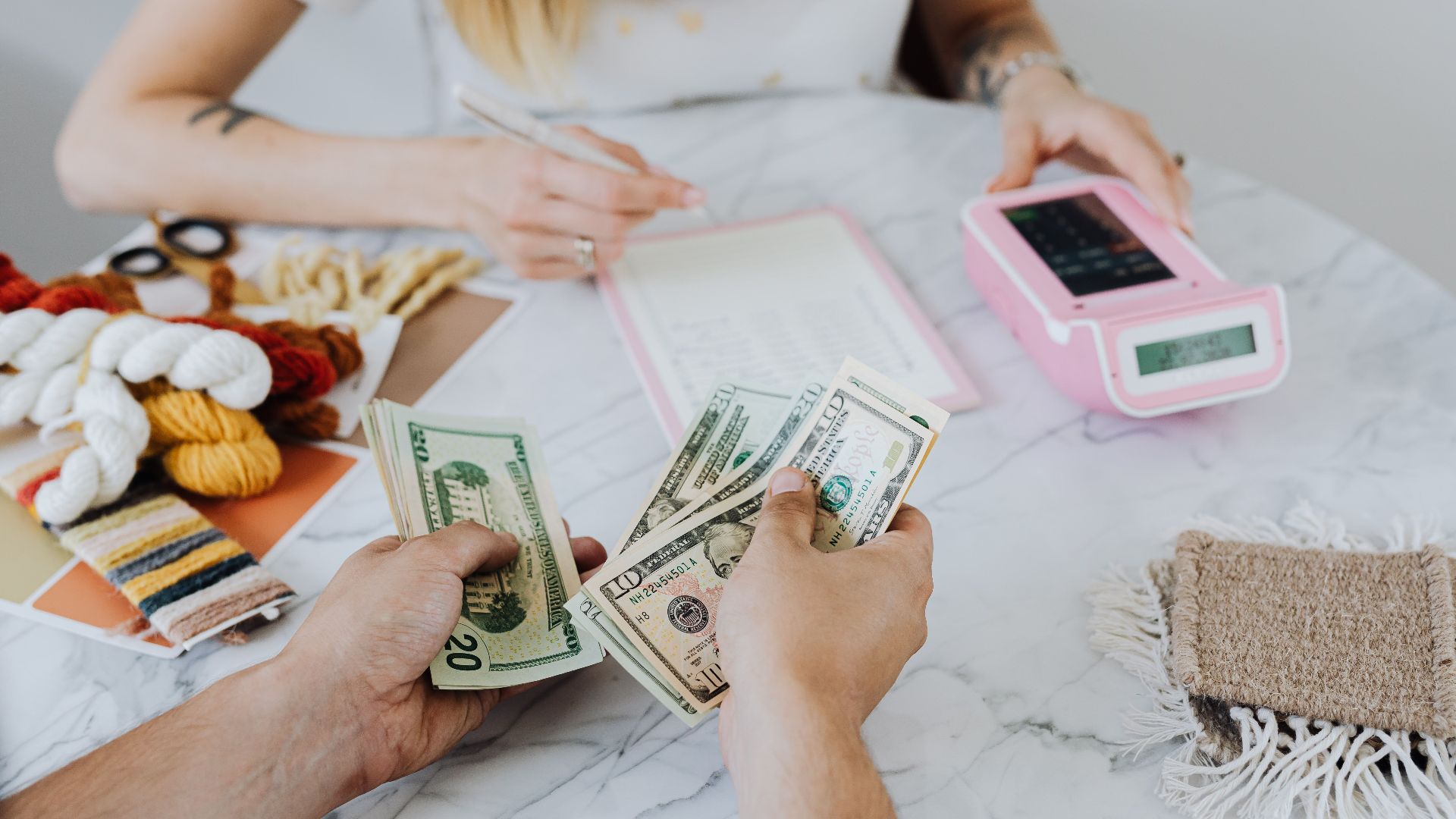 Two people handling cash and budgeting with a calculator and notebook at a table.