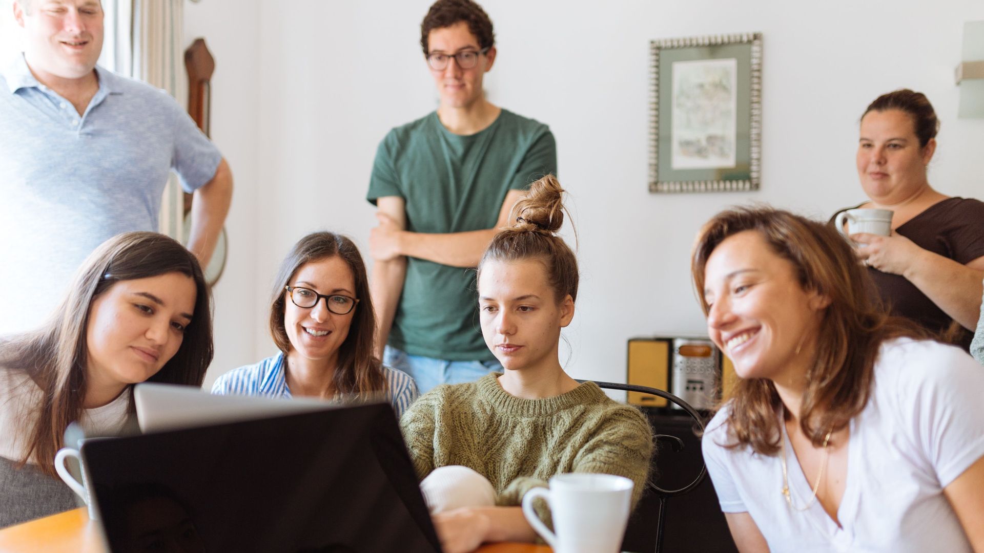 A diverse group of adults at work, enjoying a casual meeting indoors with focus and smiles.