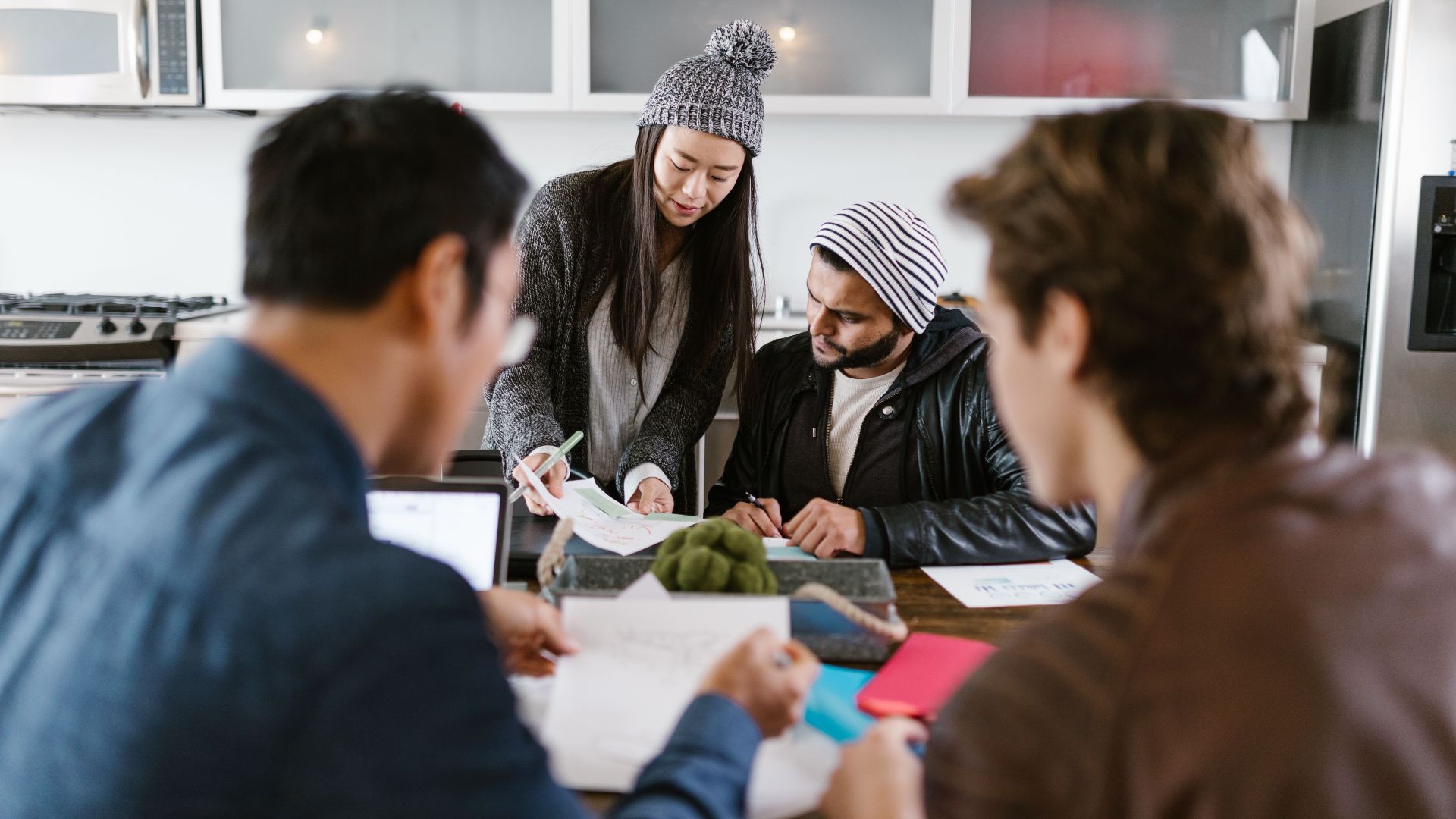 A dynamic group of young entrepreneurs brainstorming in a well-lit office space.