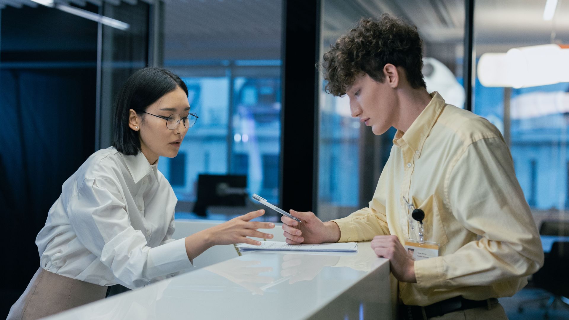 Two professionals discussing at a modern reception, highlighting teamwork and customer service.