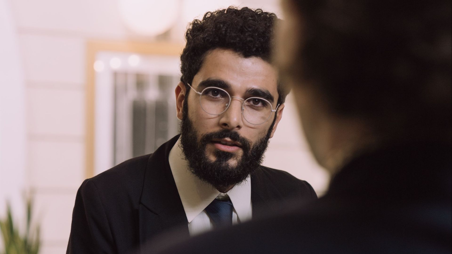 A professional businessman checks in at a hotel reception, engaging with a concierge.