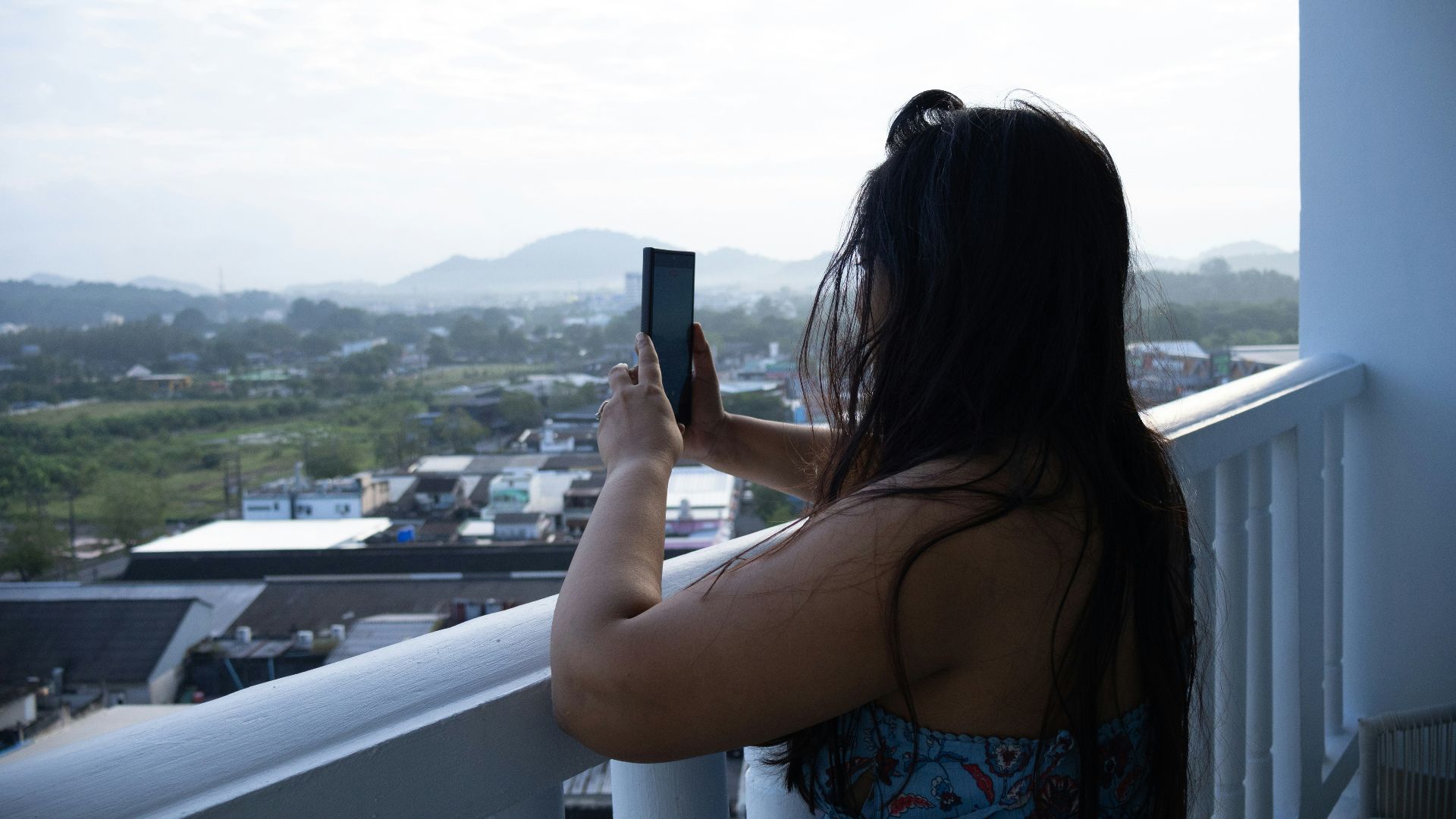 Woman taking a picture with her phone on a balcony