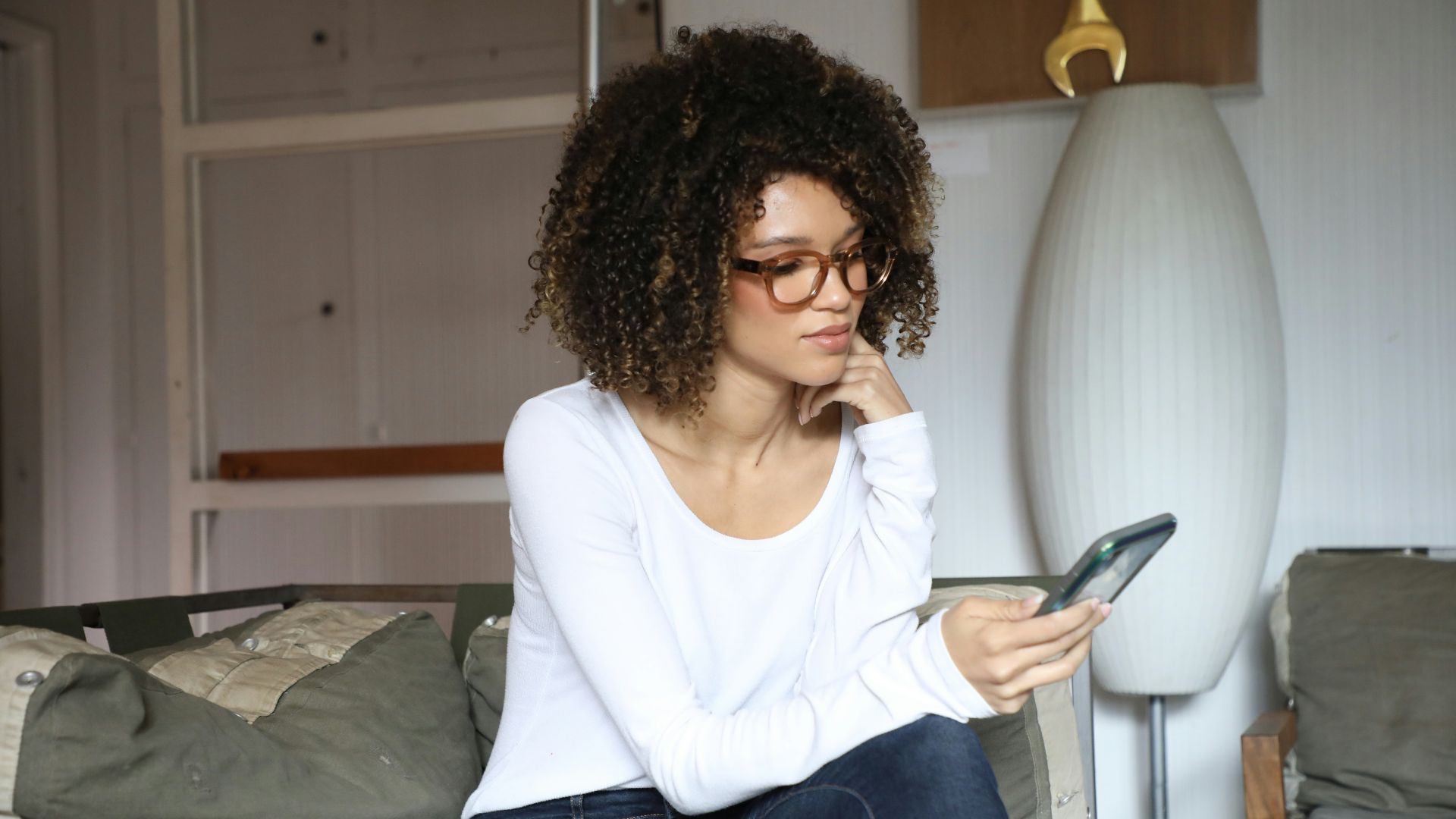 woman in white long sleeve shirt and blue denim jeans sitting on bed