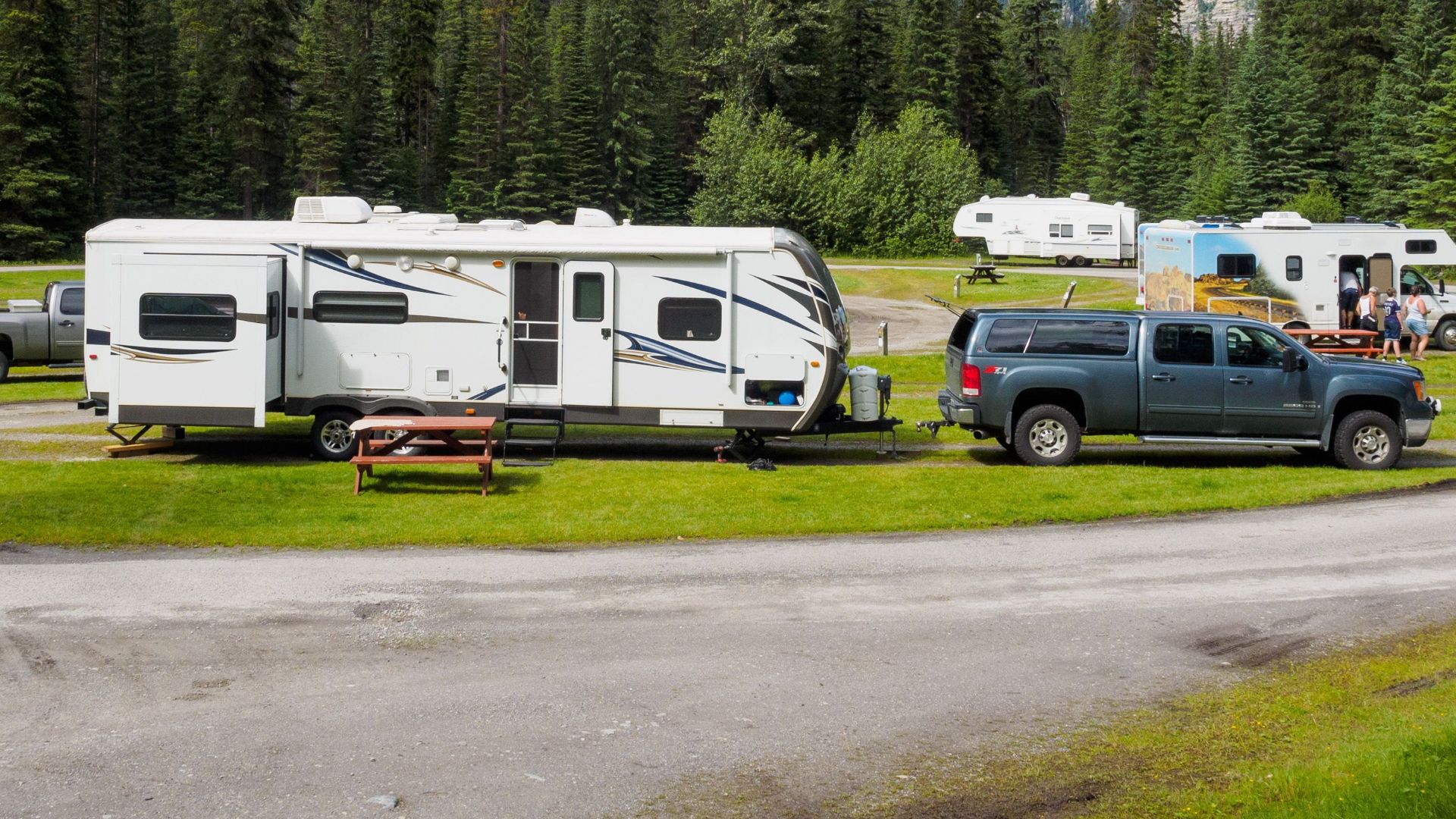 A beautiful campsite featuring RVs amidst lush forests and towering mountains for a peaceful getaway.