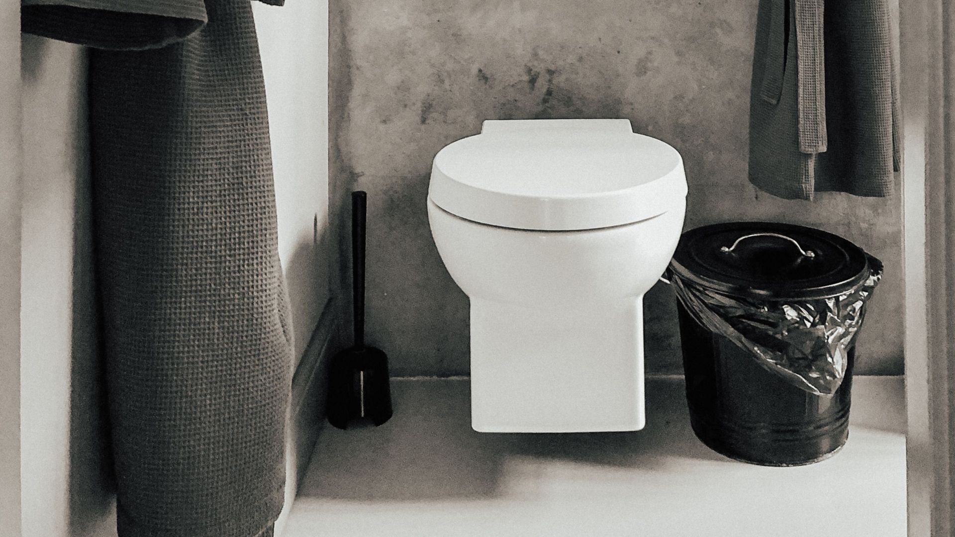Modern bathroom featuring bathrobes and a toilet in a minimalist style.
