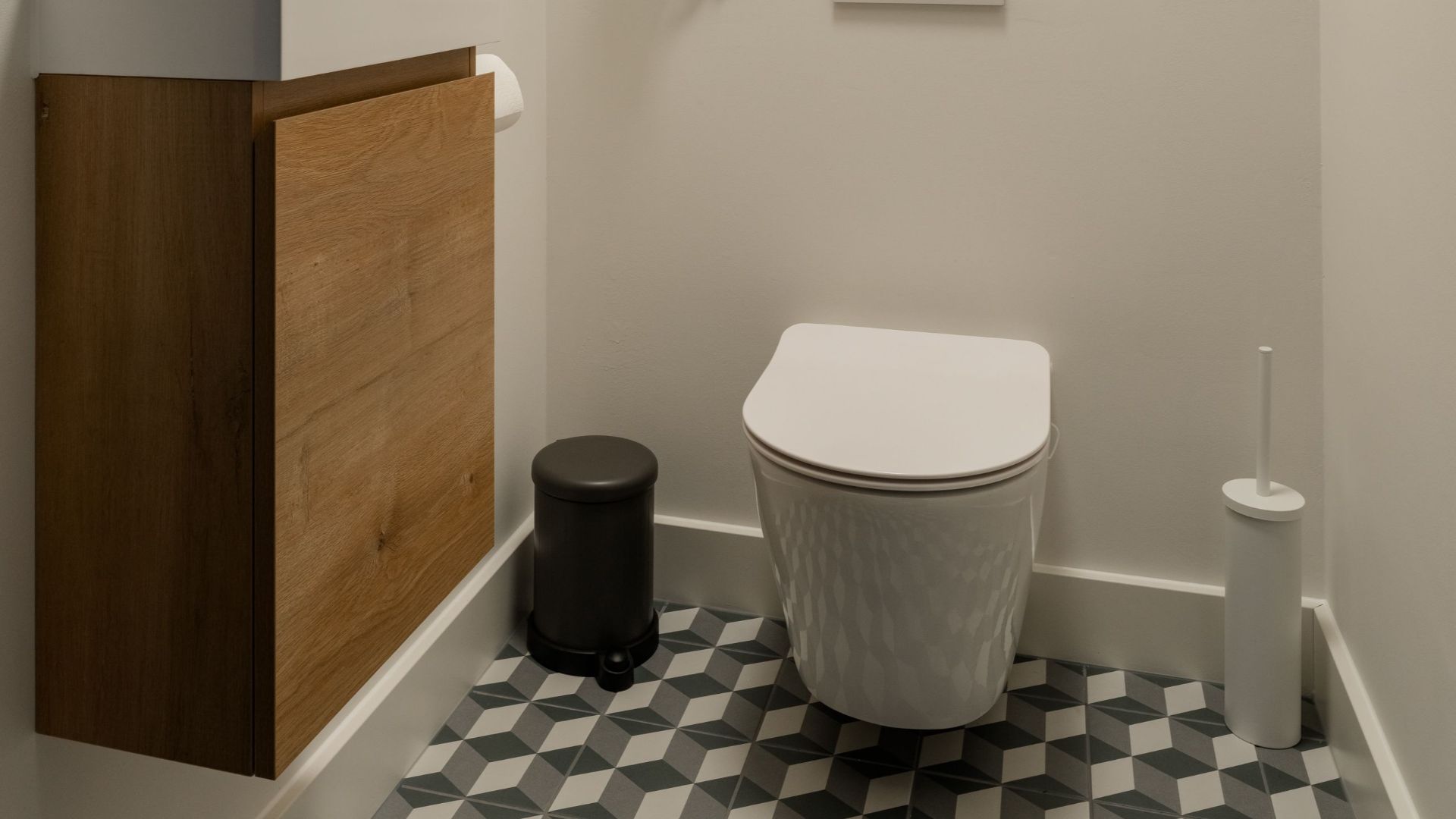 Stylish modern bathroom featuring a wooden vanity, geometric tiles, and round mirror.