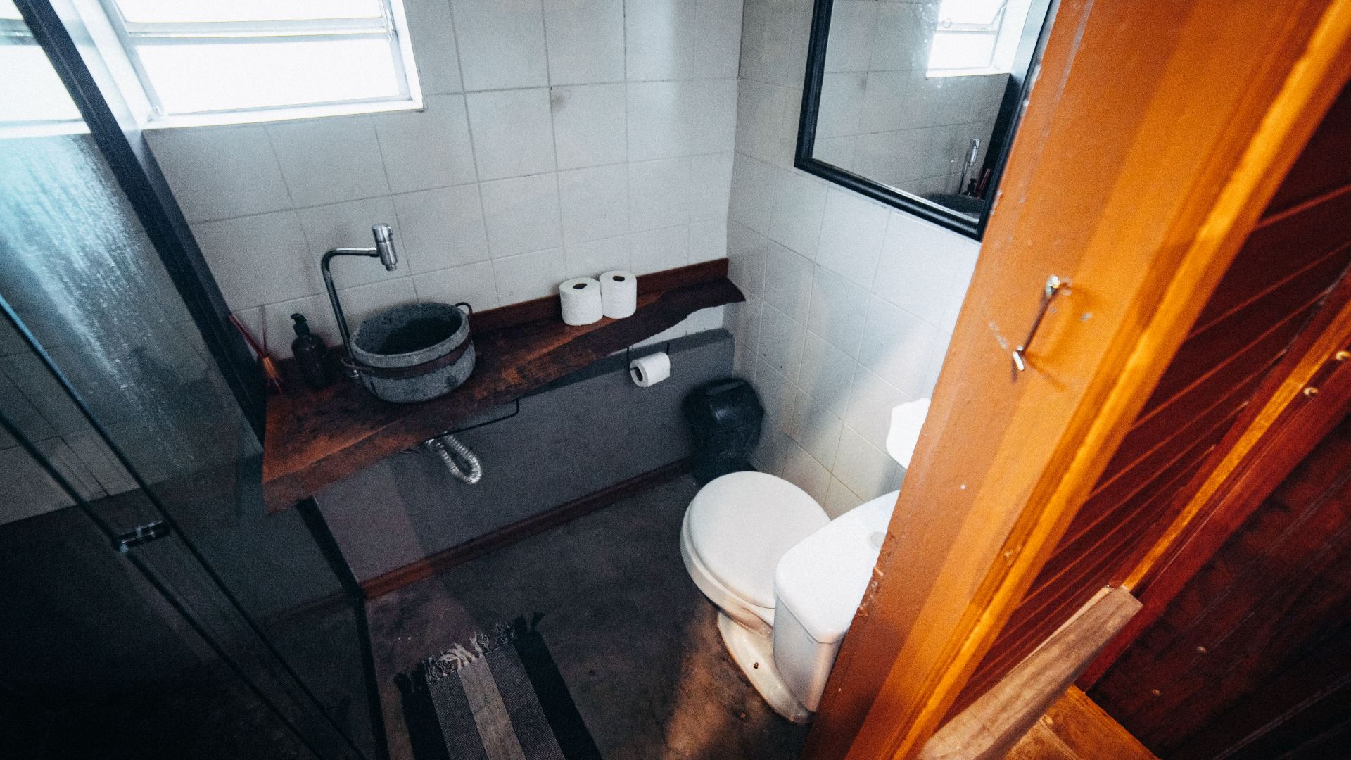 A modern minimalist bathroom featuring a unique stone basin and rustic wood elements, perfect for interior inspiration.