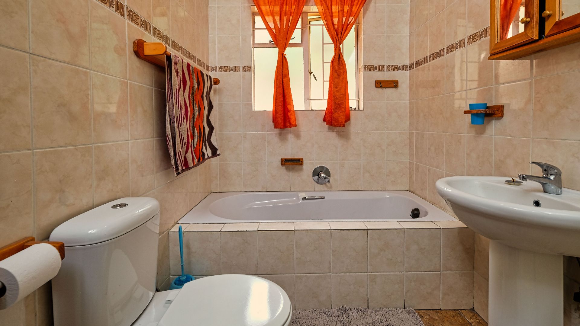 A warm and inviting bathroom featuring modern fixtures and orange curtains.
