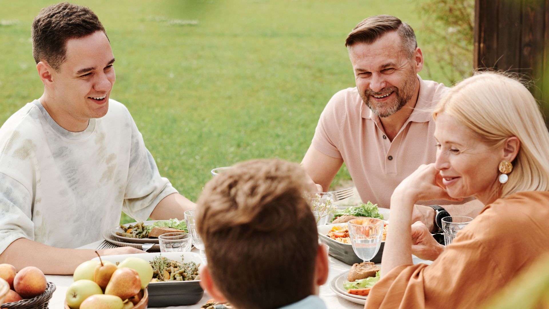 A cheerful family enjoying a meal together outdoors, sharing laughter and warmth.