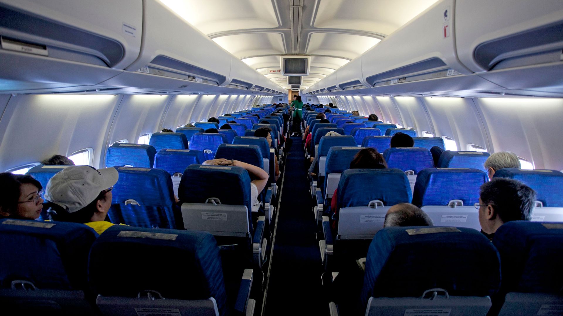 Symmetrical view of passengers inside a commercial airplane cabin during daytime travel.