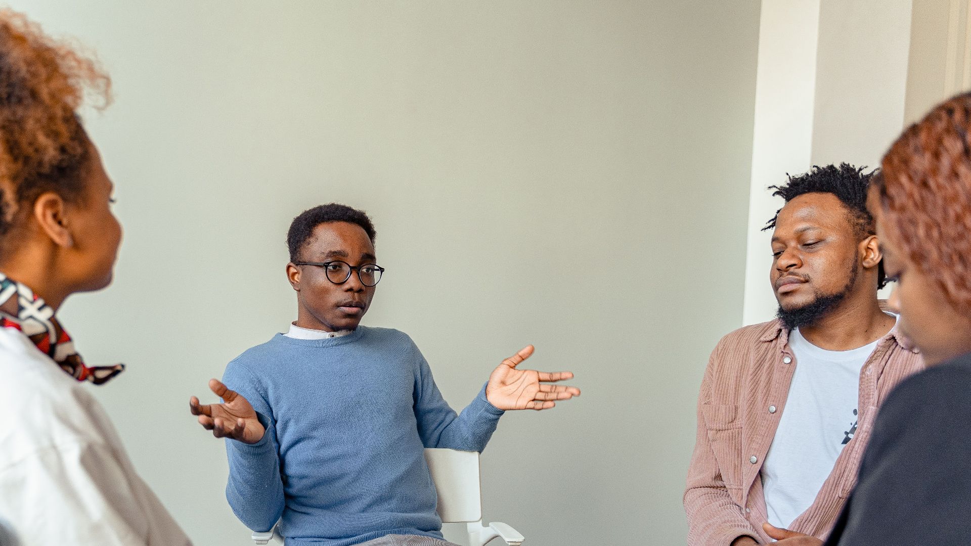 Diverse group therapy session with young adults and a mental health professional indoors.