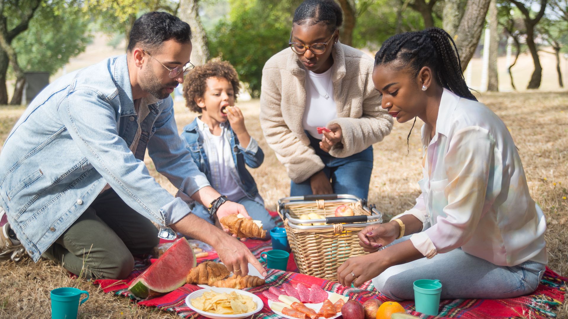 Family and friends enjoying a summer picnic with food and fun in a sunny park.