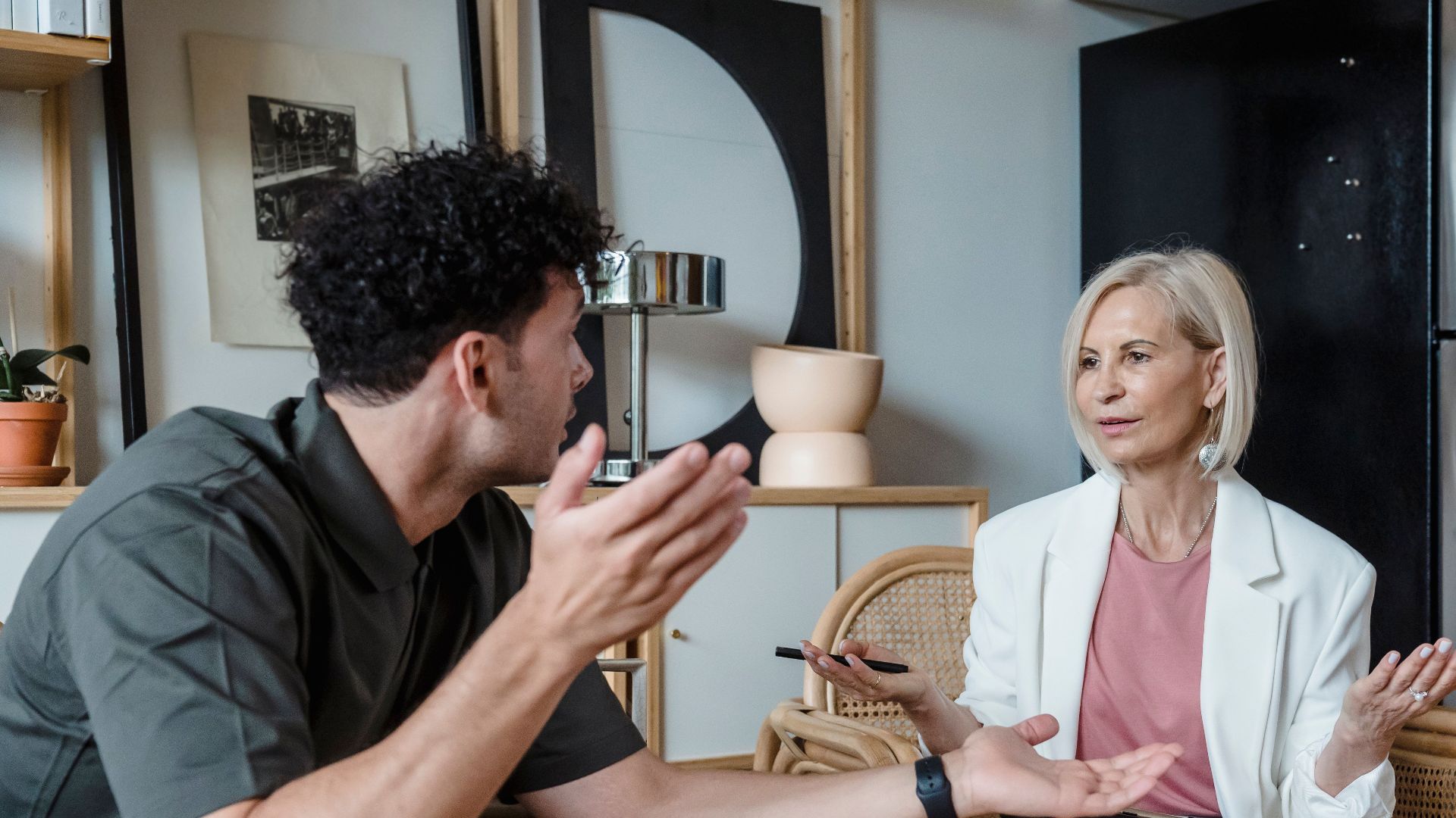 Two adults engaged in a lively discussion in a stylish indoor setting, illustrating communication and connection.