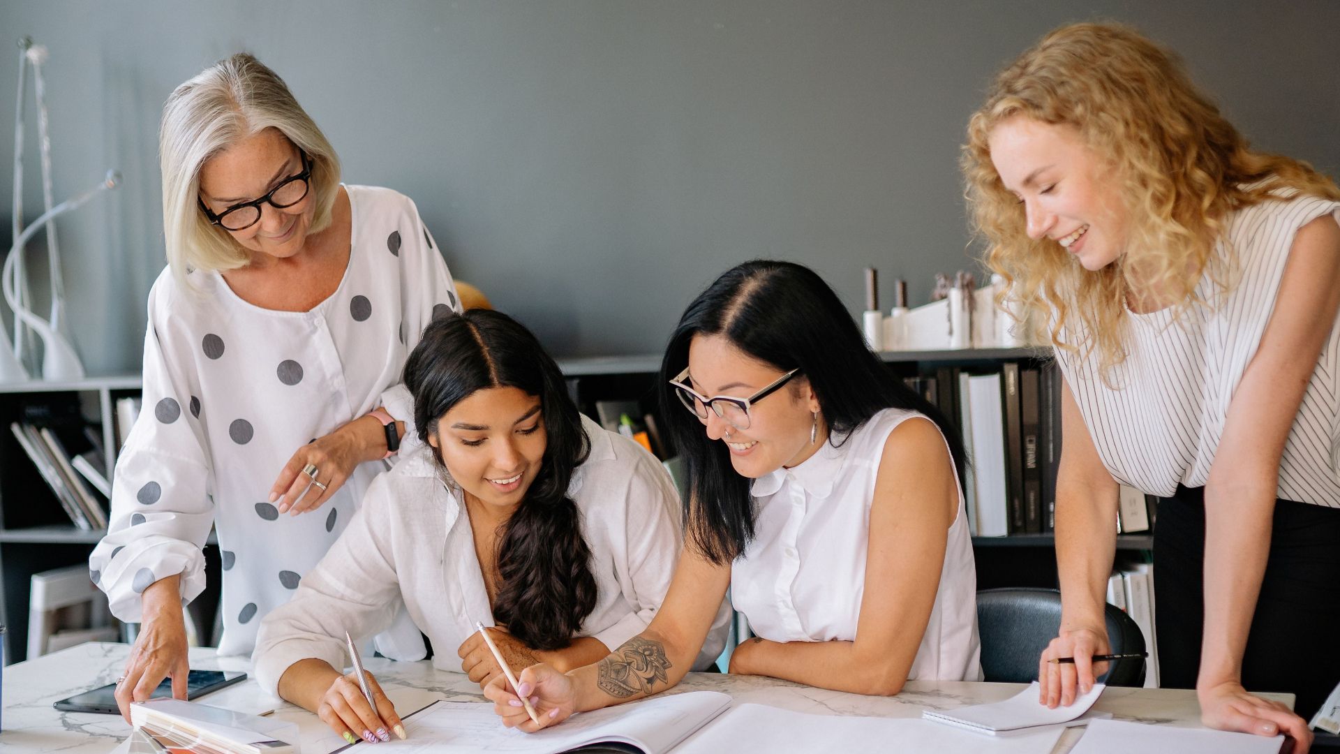 Four diverse women brainstorming ideas in a modern office environment with enthusiasm.
