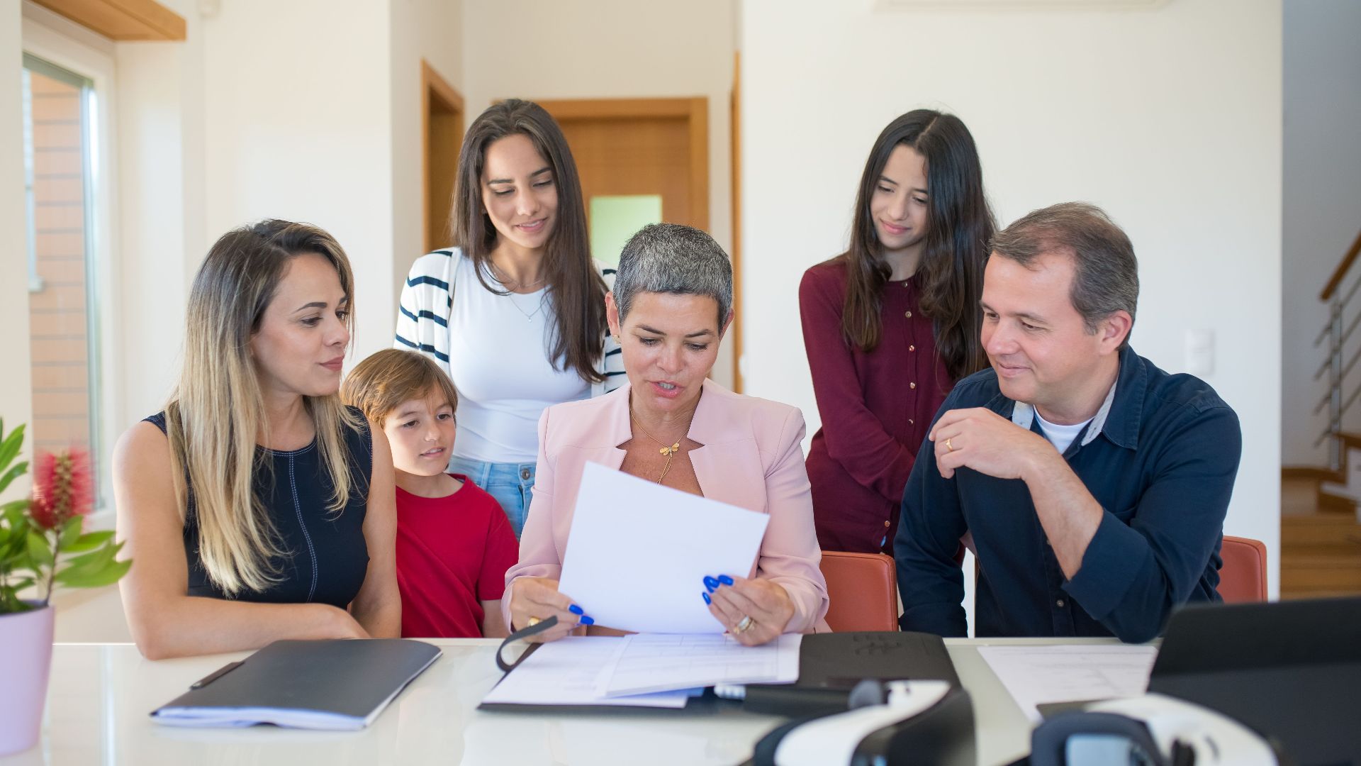 A family meeting with a female realtor reviewing documents in a bright, modern room.