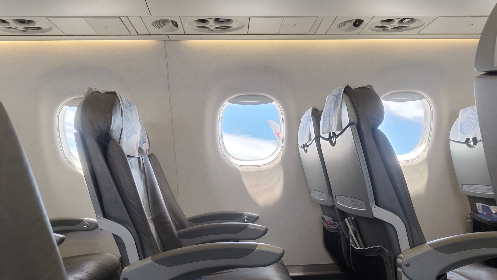Interior of an empty airplane cabin featuring window view of sky and clouds, perfect for travel theme.