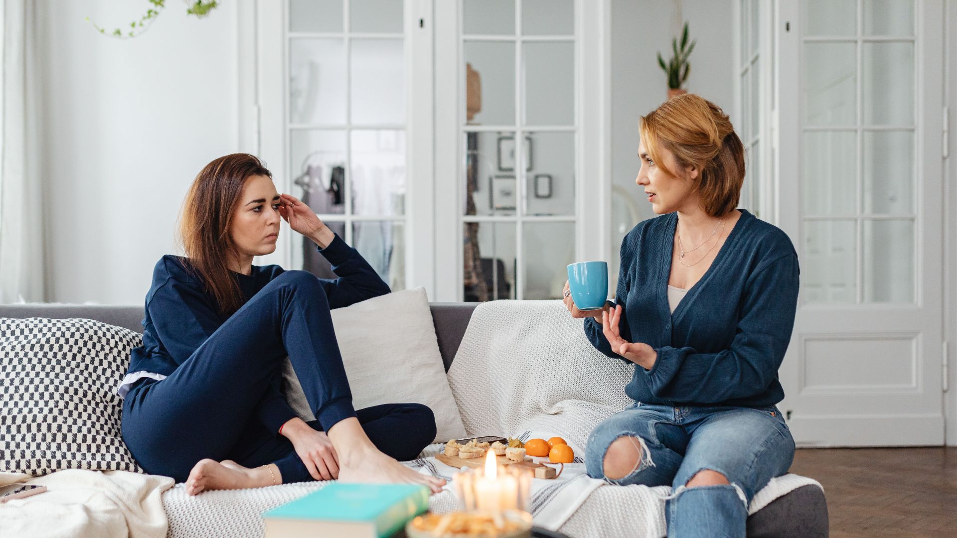 Two women having a heartfelt conversation in a modern living room setting.