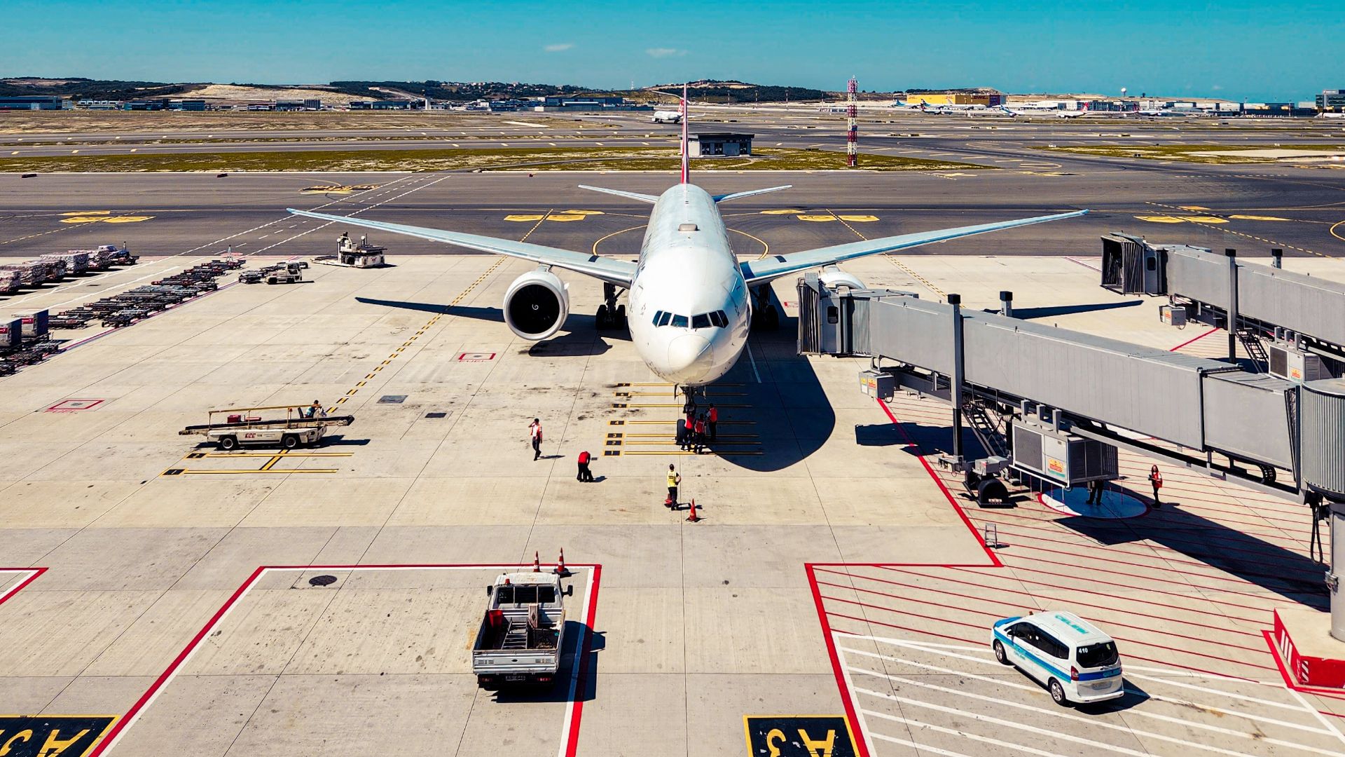 Airplane parked at airport gate, ready for passenger boarding under clear blue skies.