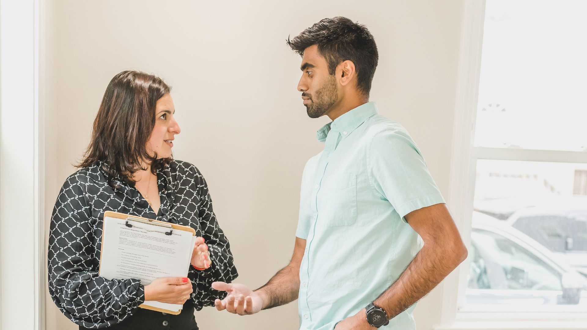 Real estate agent and client in business attire discussing a contract indoors.
