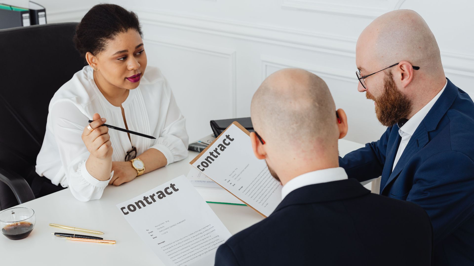 Three business professionals in discussion over a contract in a modern office setting.