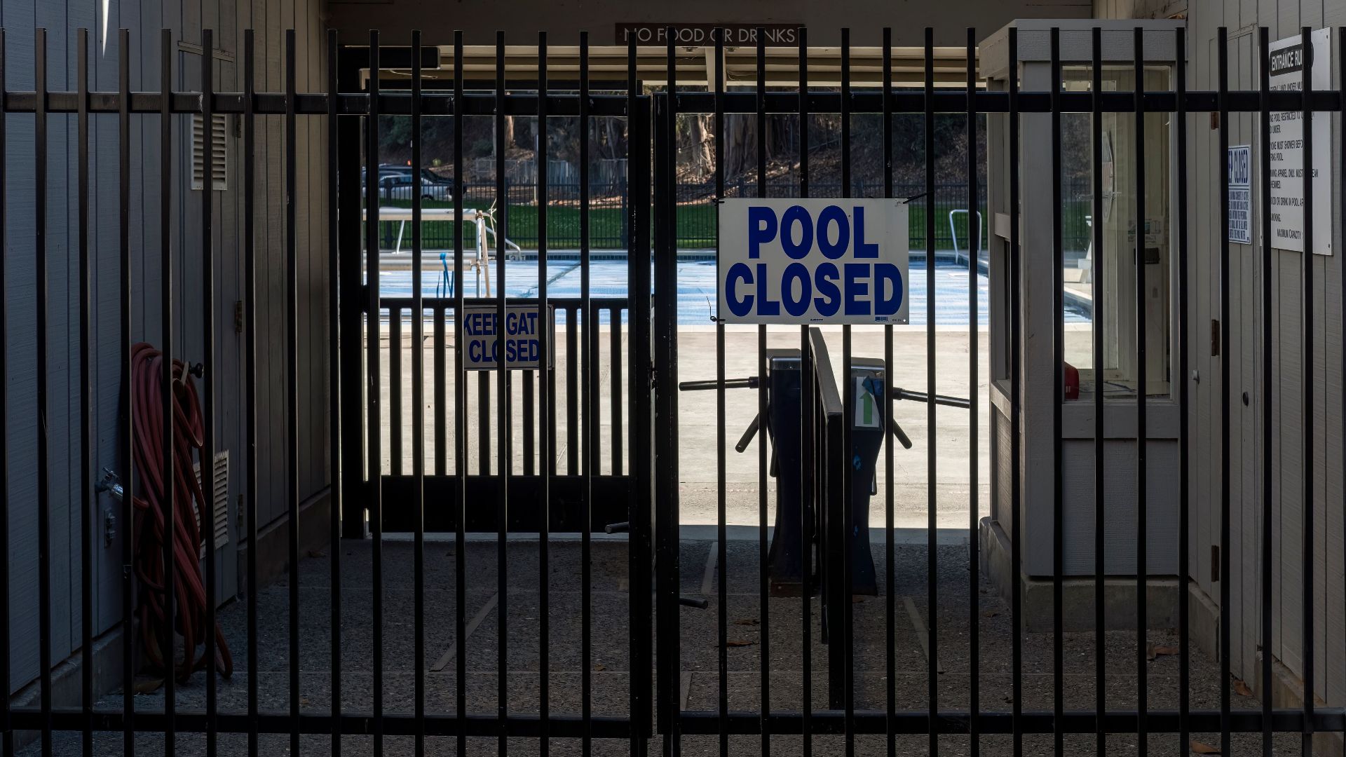 Iron gate blocking a closed community pool entrance with a clear sign.