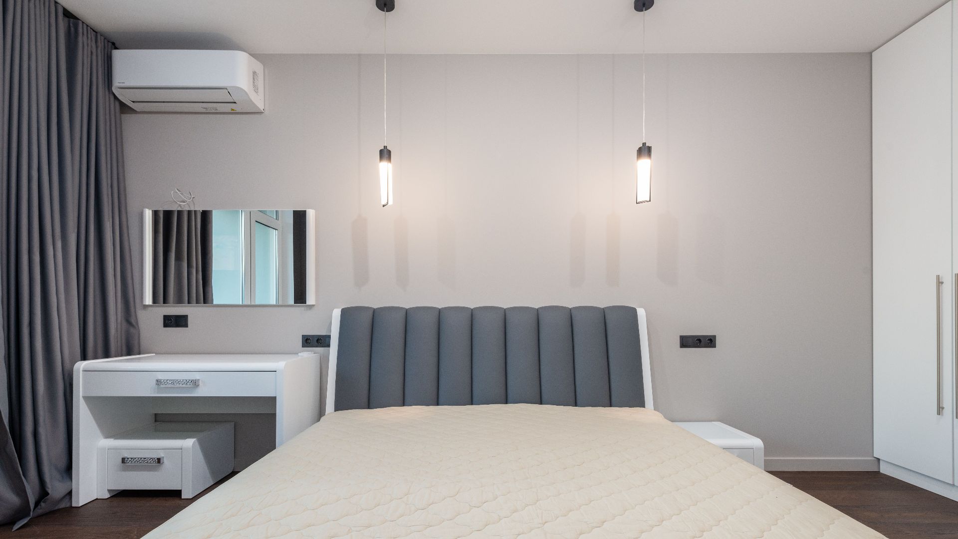 Sleek minimalist bedroom design featuring a plush bed, pendant lighting, and modern furnishings.