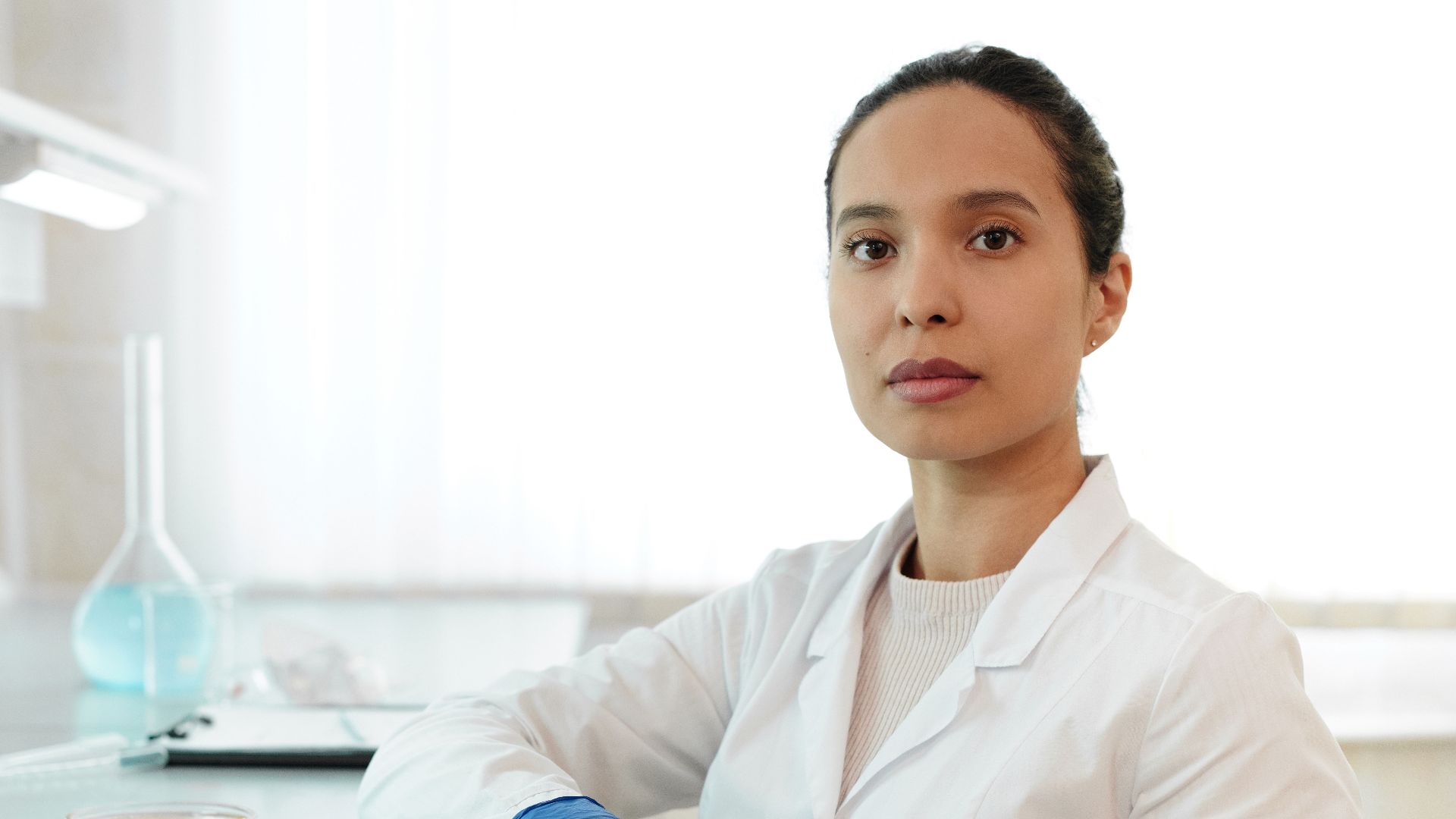 Female scientist in a lab coat conducting research with laboratory glassware.