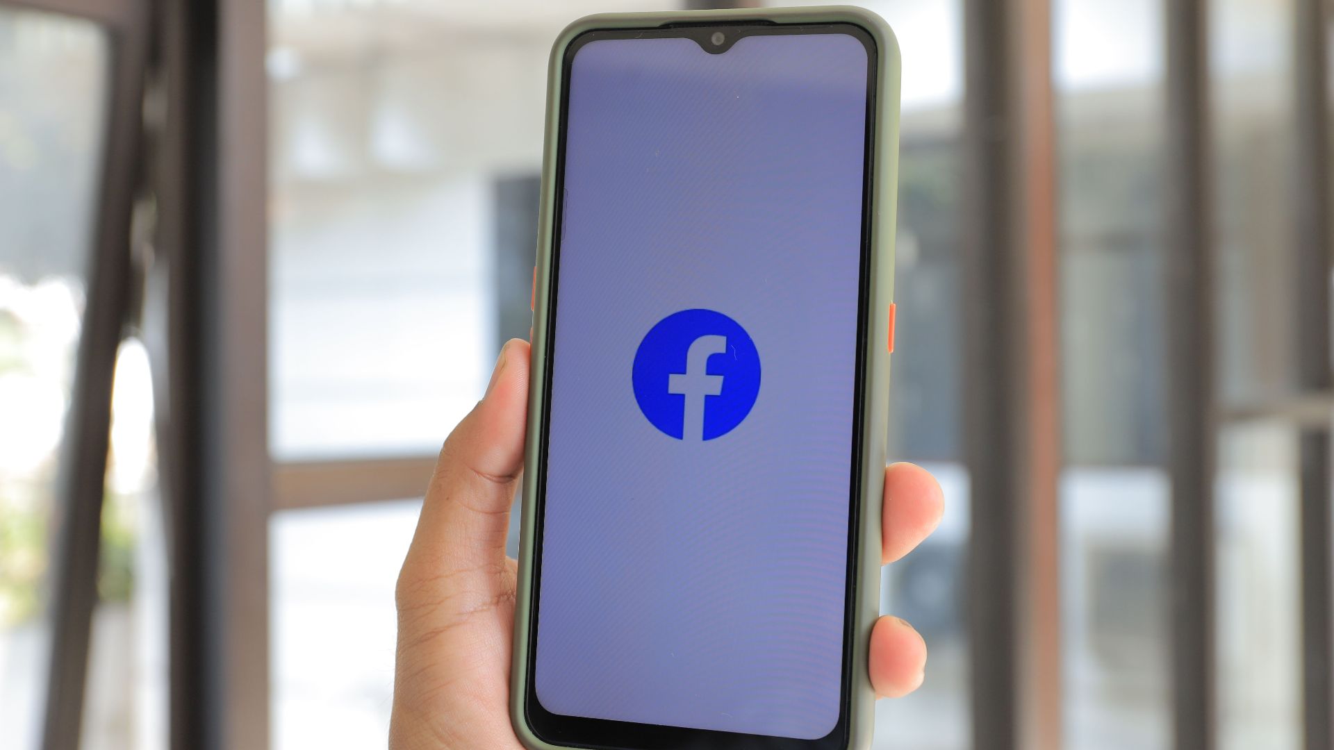 Close-up of smartphone with Facebook app open held by hand indoors.