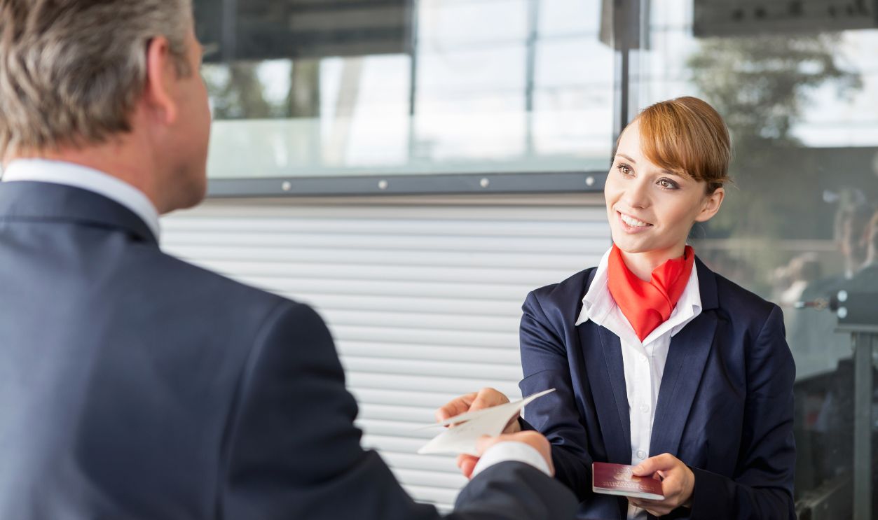 Shutterstock-1656482917, Passenger service agent giving businessman passport and boarding pass in check in area at airport