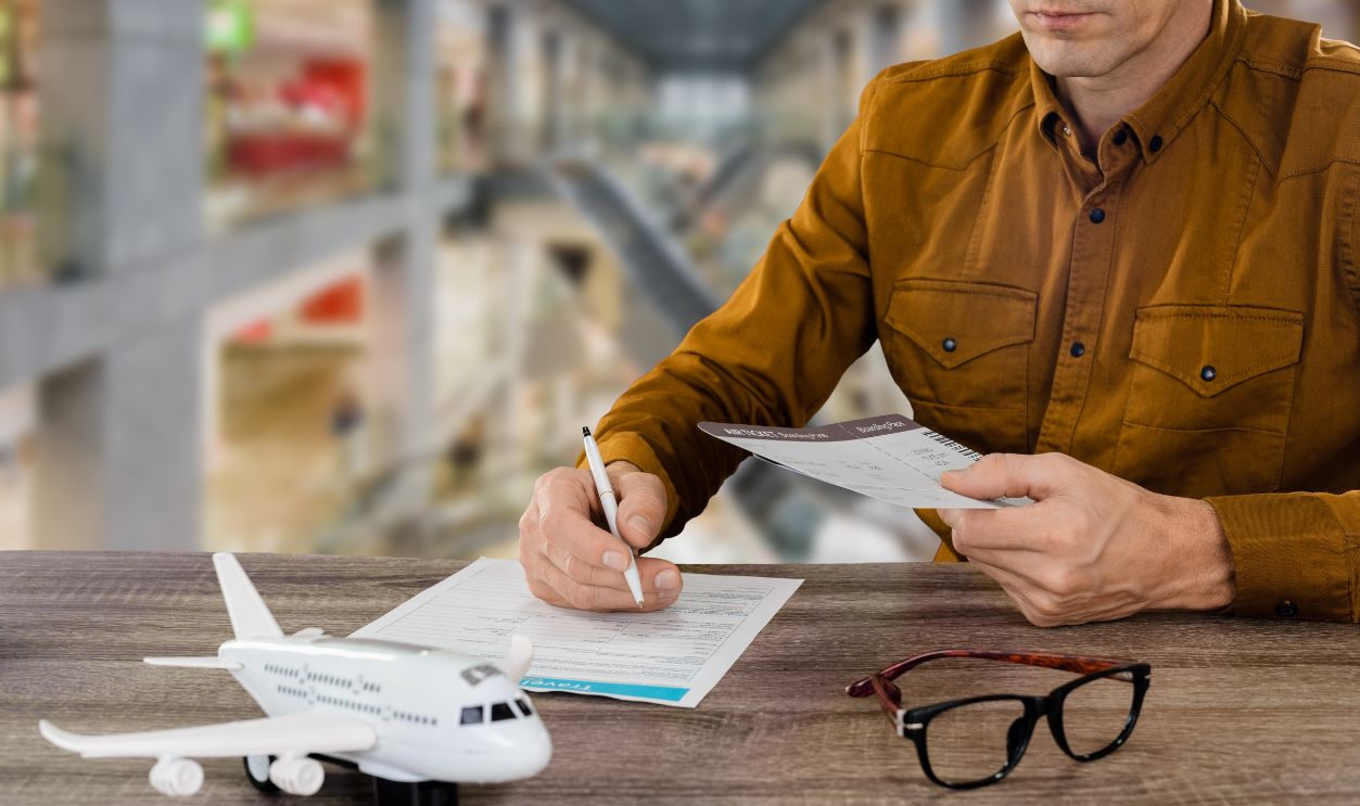 Young male traveler signing travel insurance policy booklet in airport