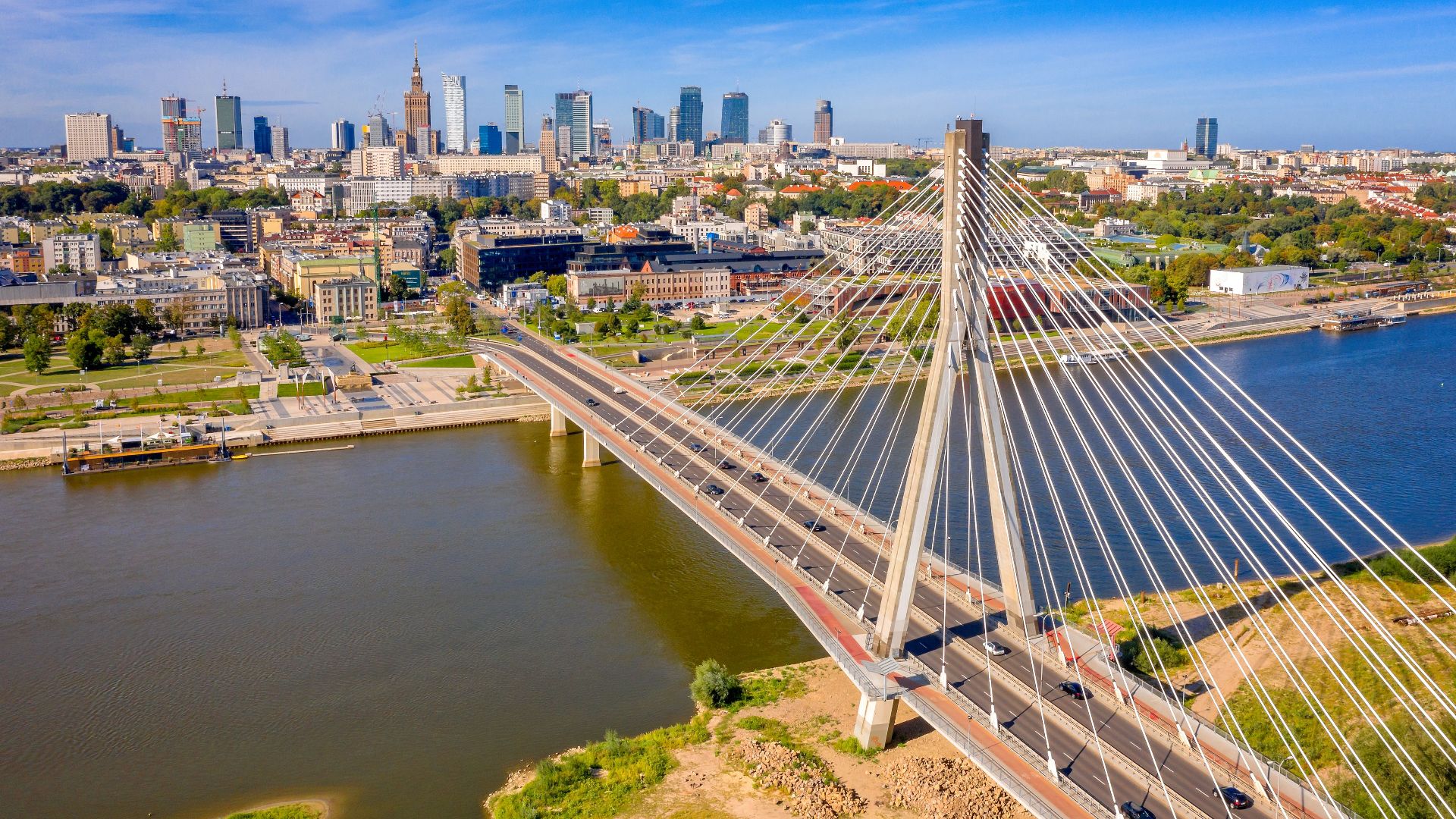 Stunning aerial shot of Świętokrzyski Bridge spanning the Vistula River in Warsaw, Poland, with the city skyline.