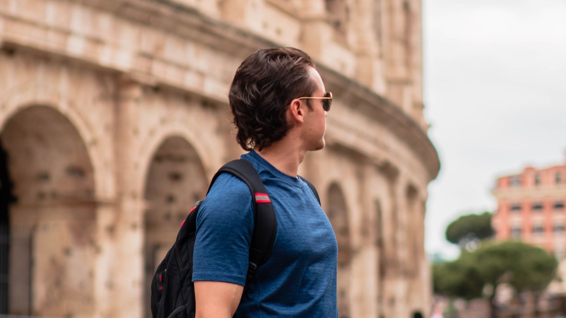 Man standing near the famous Colosseum in Rome, Italy, showcasing Roman architecture.