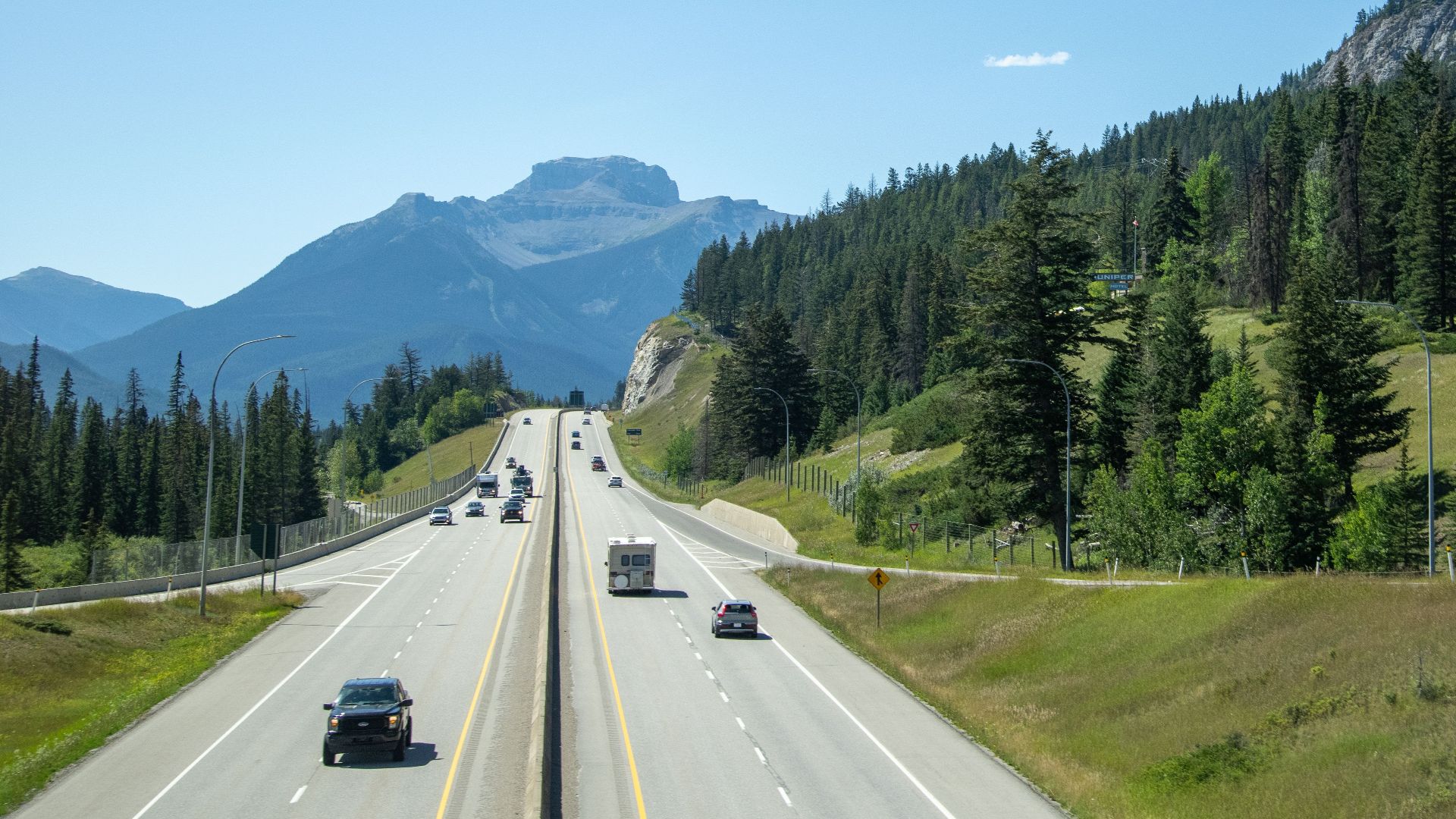 A picturesque highway scene in Banff National Park with mountains and lush greenery.