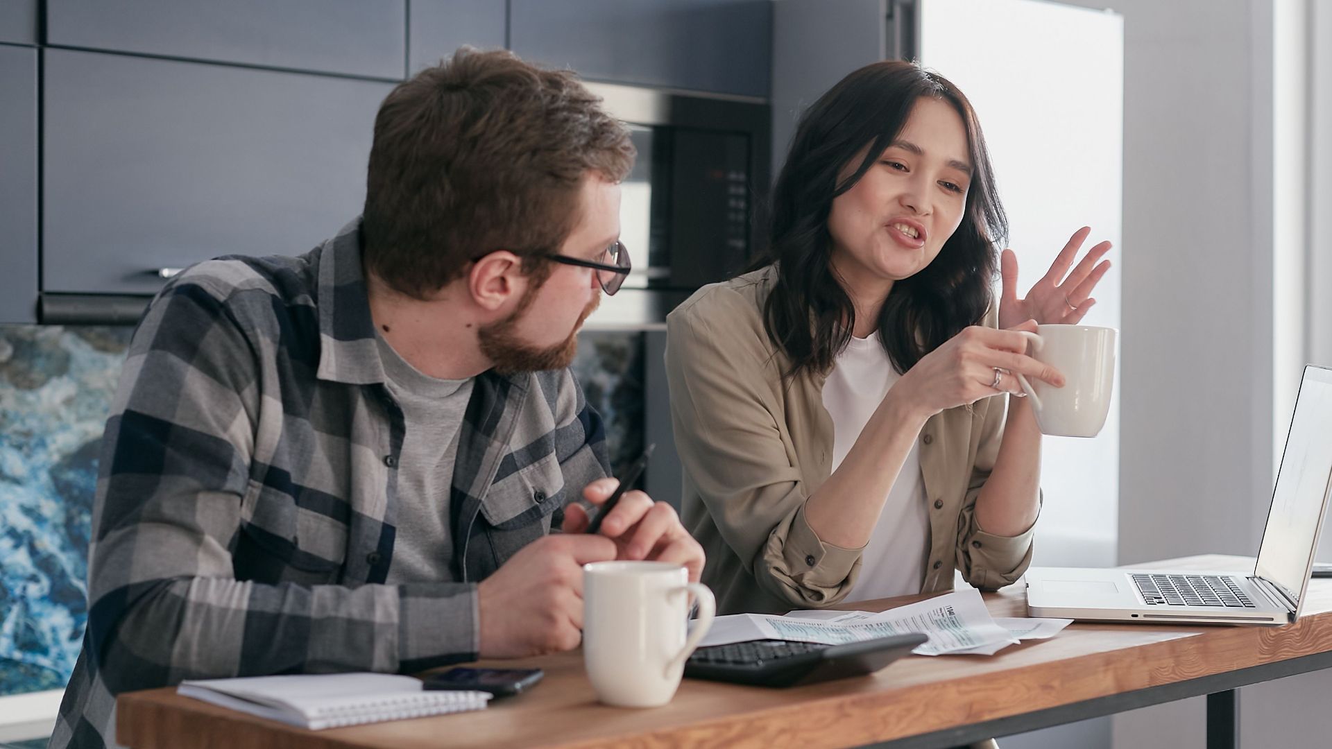 A couple having a discussion with coffee and laptops, reflecting relationship communication indoors.