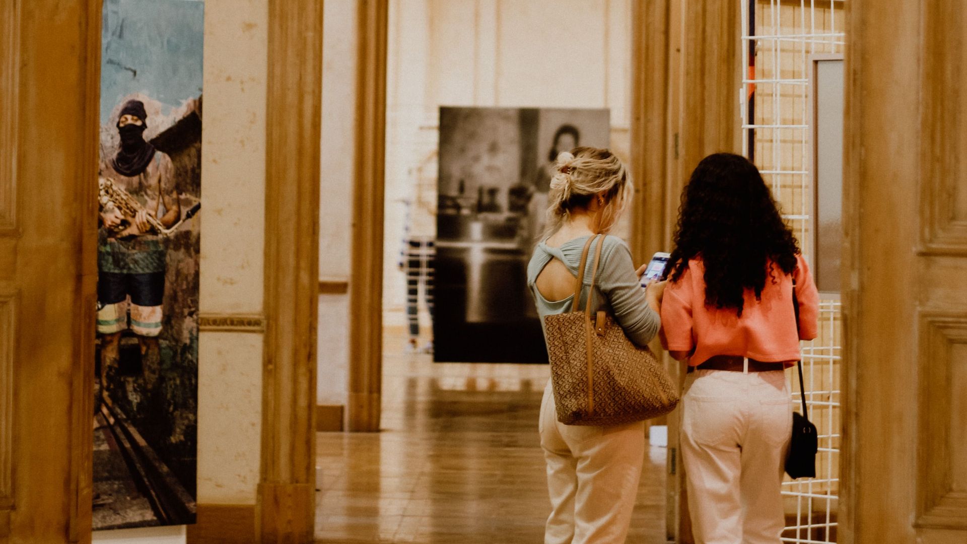 Two women admire artwork in an elegant Istanbul gallery hallway.