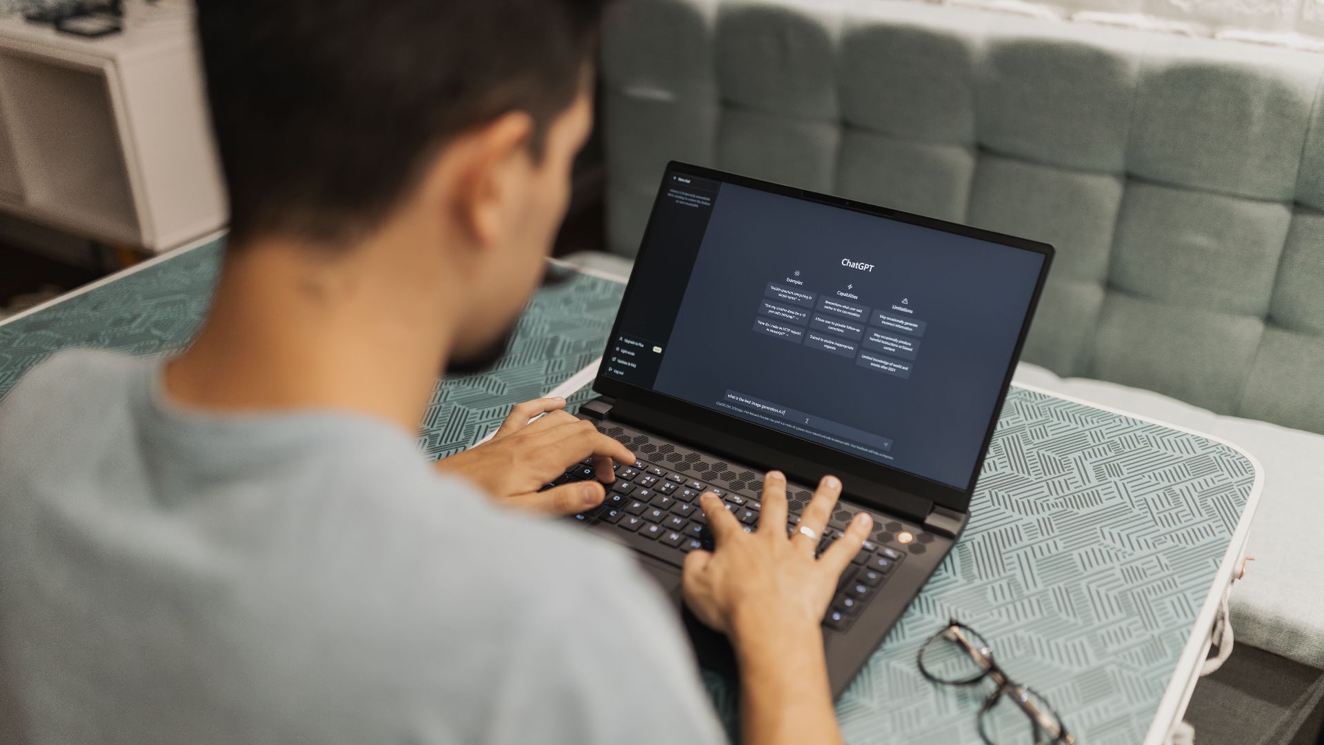 A man working on a laptop displaying ChatGPT's interface in an indoor setting.