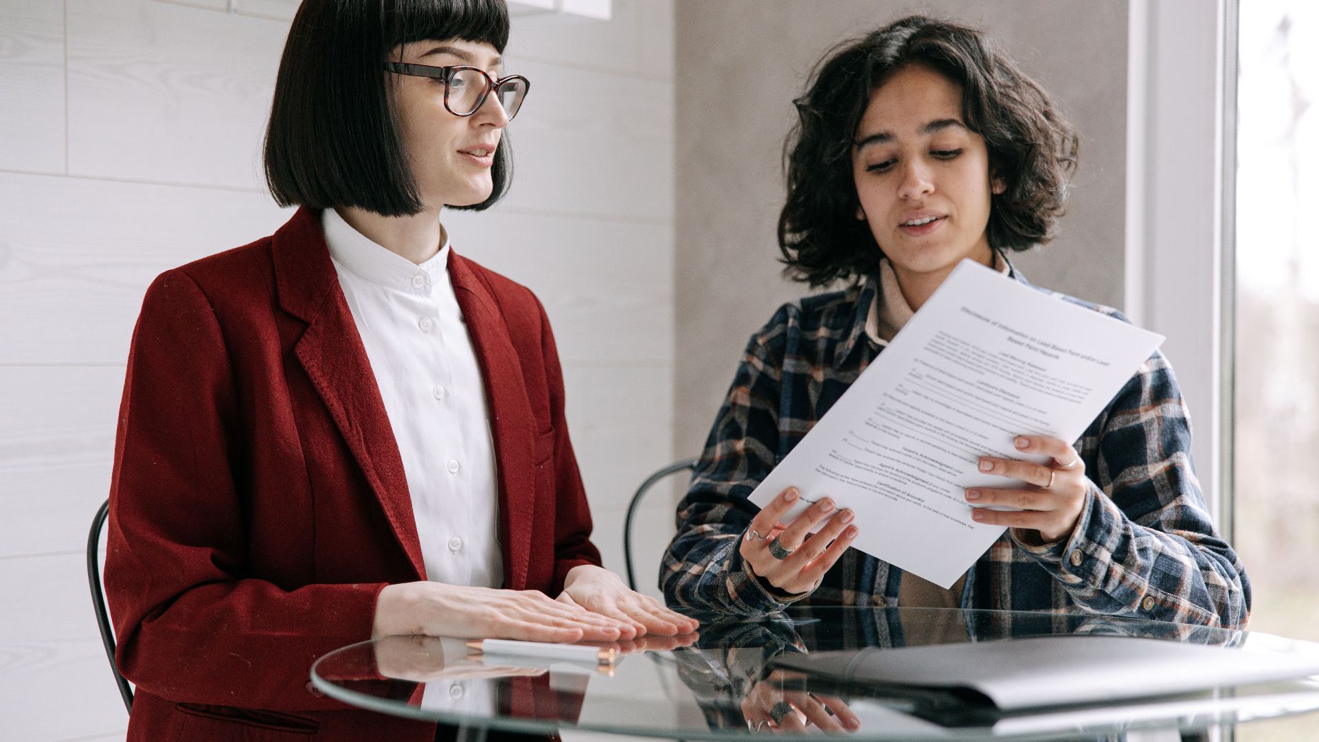 Two women reviewing real estate documents, indicating a decision or agreement indoors.