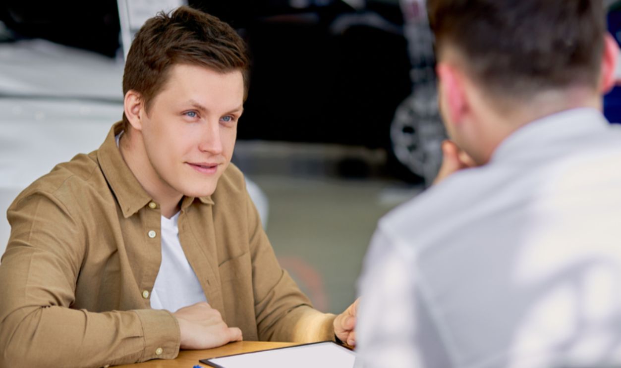 Shutterstock-1745302445, serious customer listen to salesman before signing document, making purchase in dealership