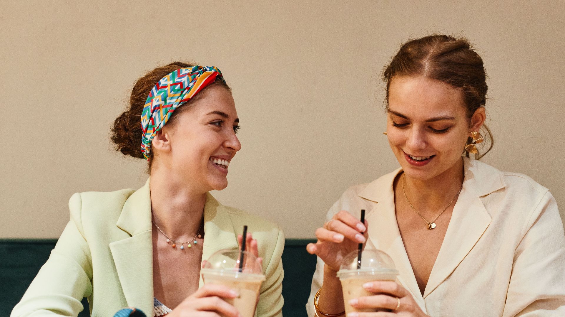 Two young women having a lively conversation over iced coffee at a café.