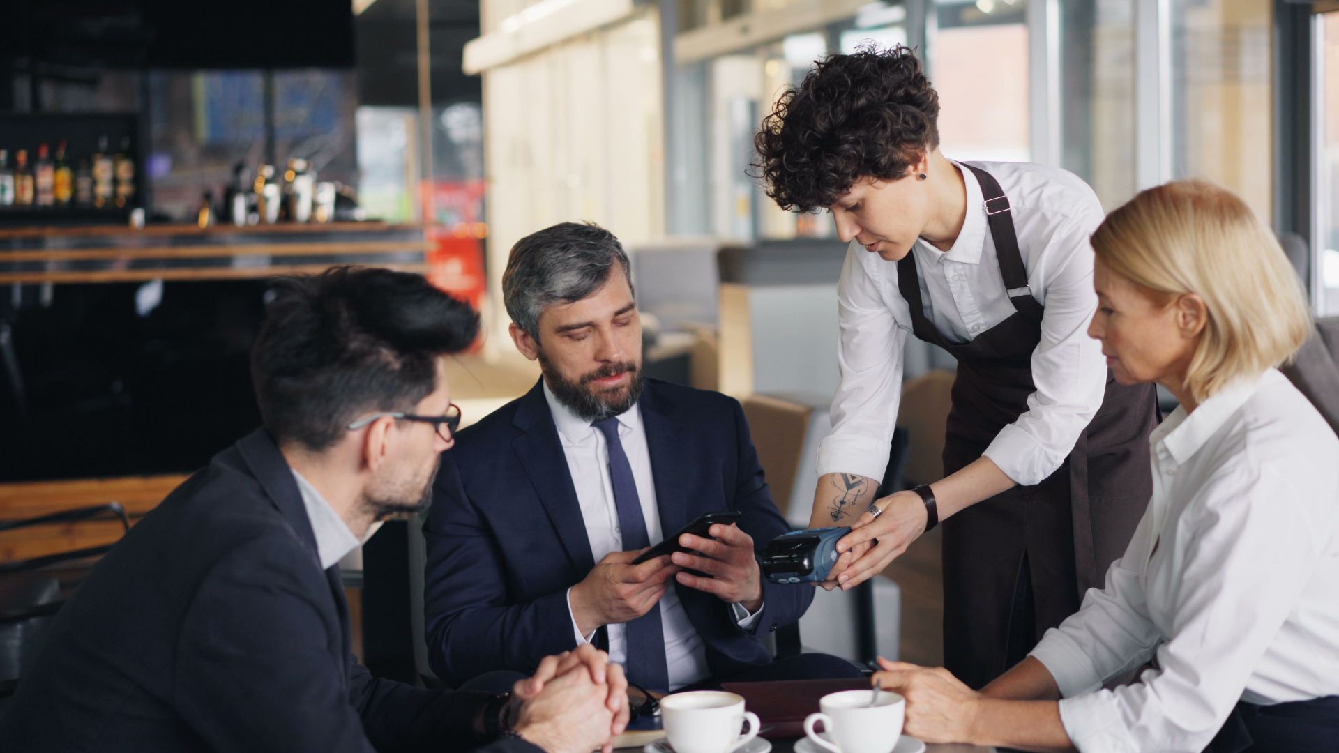 Business professionals in a cafe settling payment with a waiter.
