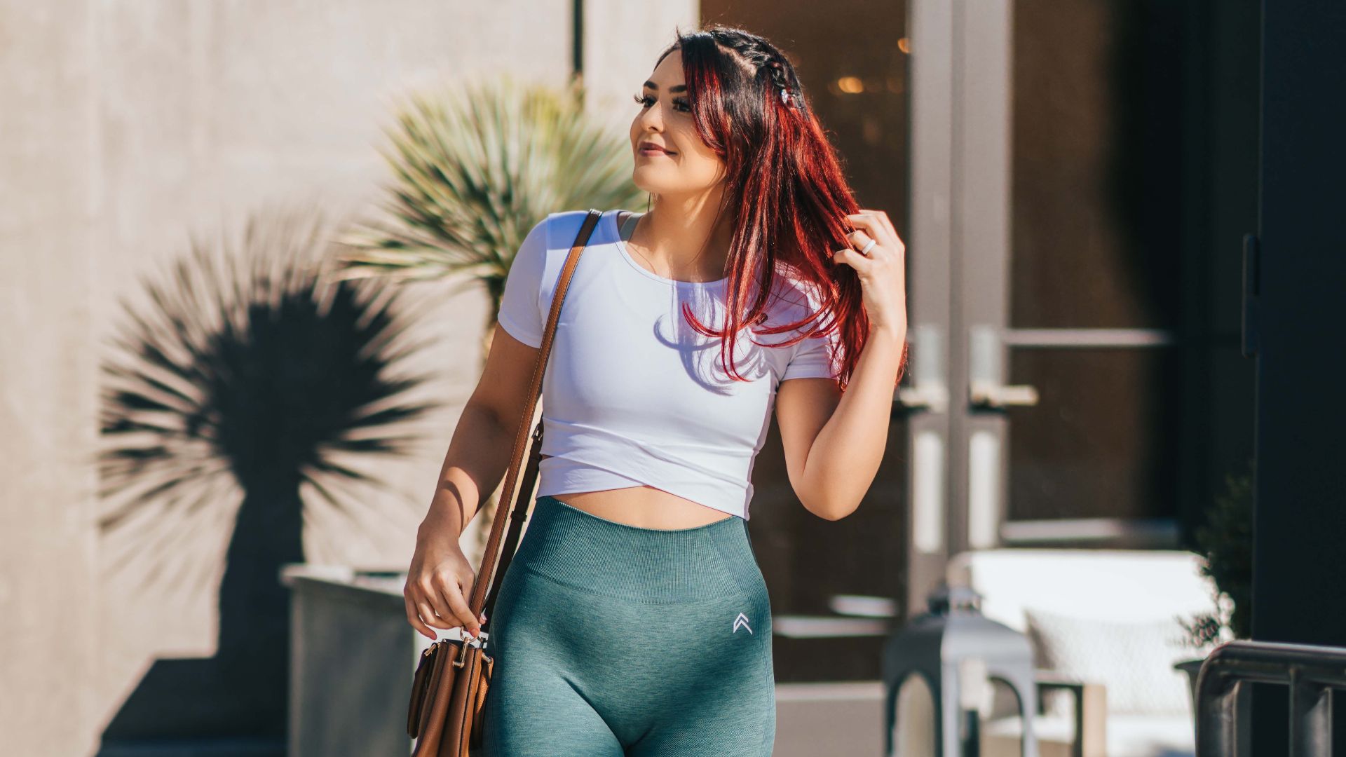 Woman in fitness attire enjoying a sunny day in Las Vegas, showcasing modern fashion with a crop top and leggings.