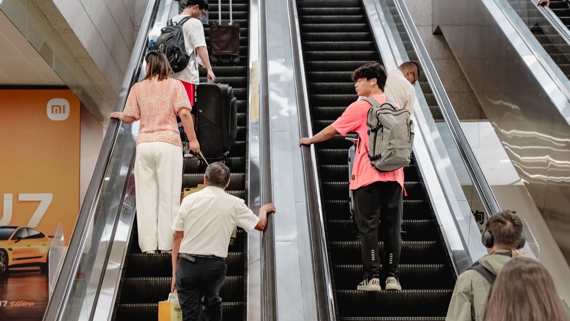 People on escalators at a bustling Shanghai metro station, showcasing urban life and commuting.