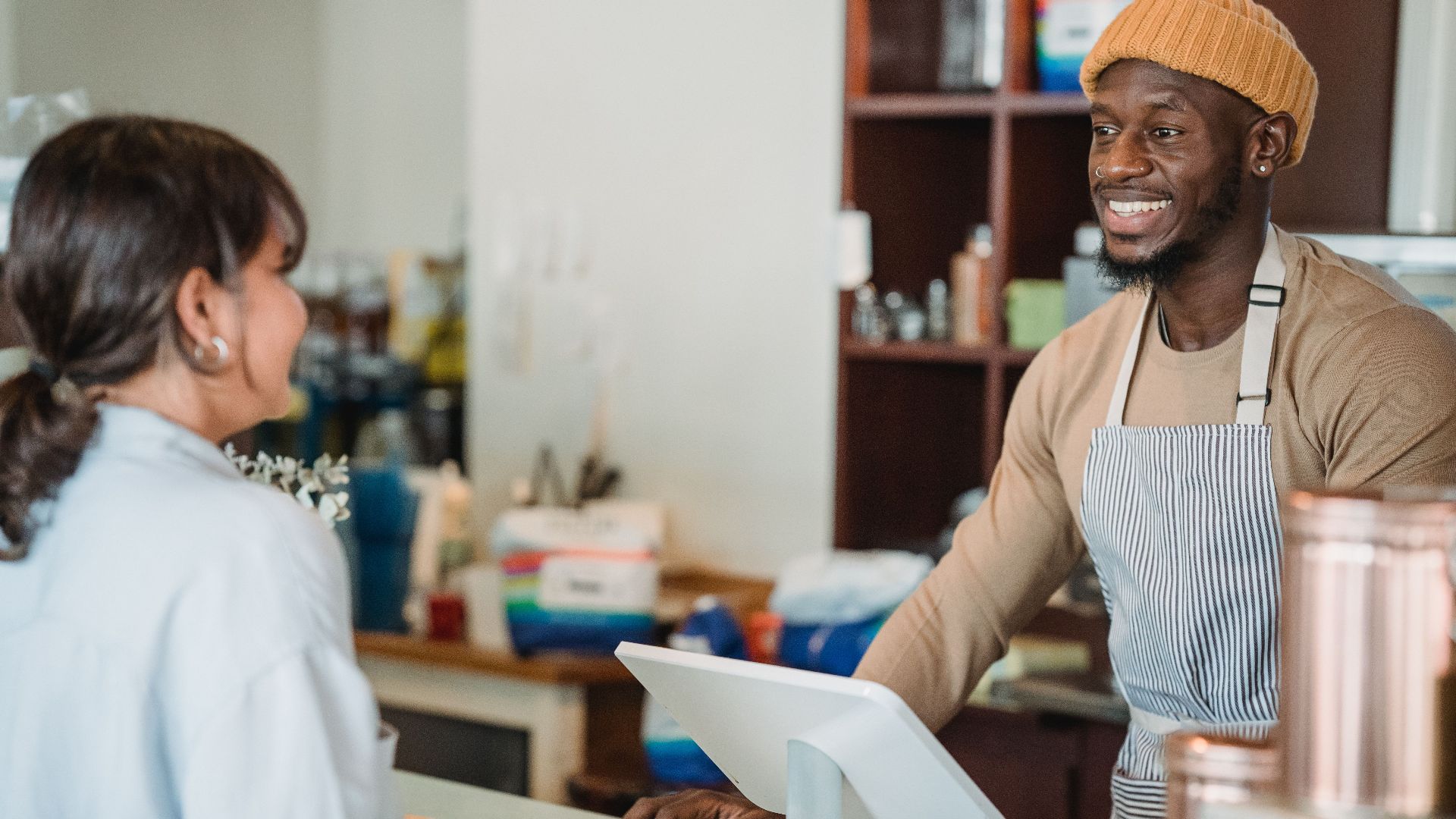 A cheerful barista engaging with a customer at a café counter, creating a welcoming atmosphere.