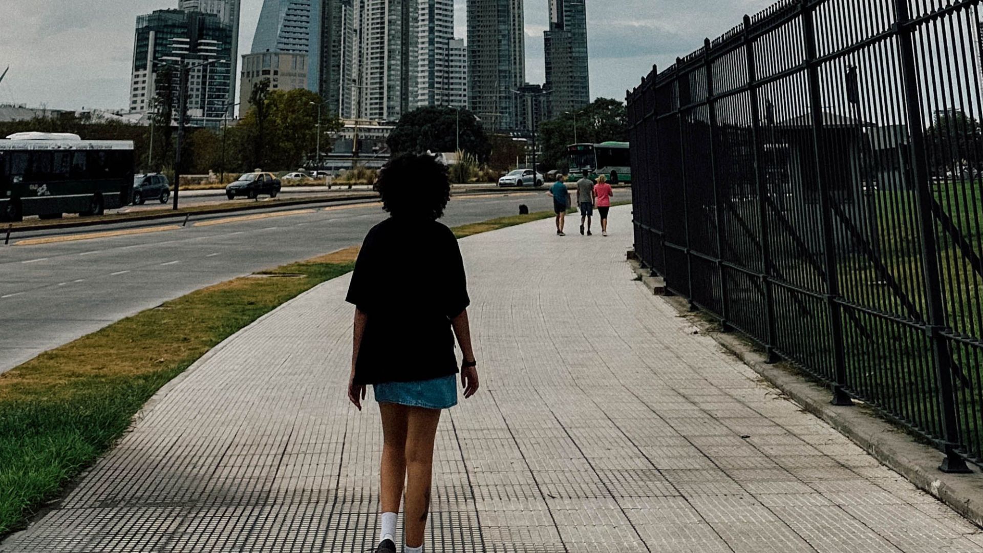 A person walking on a sidewalk with the Buenos Aires skyline in the background.