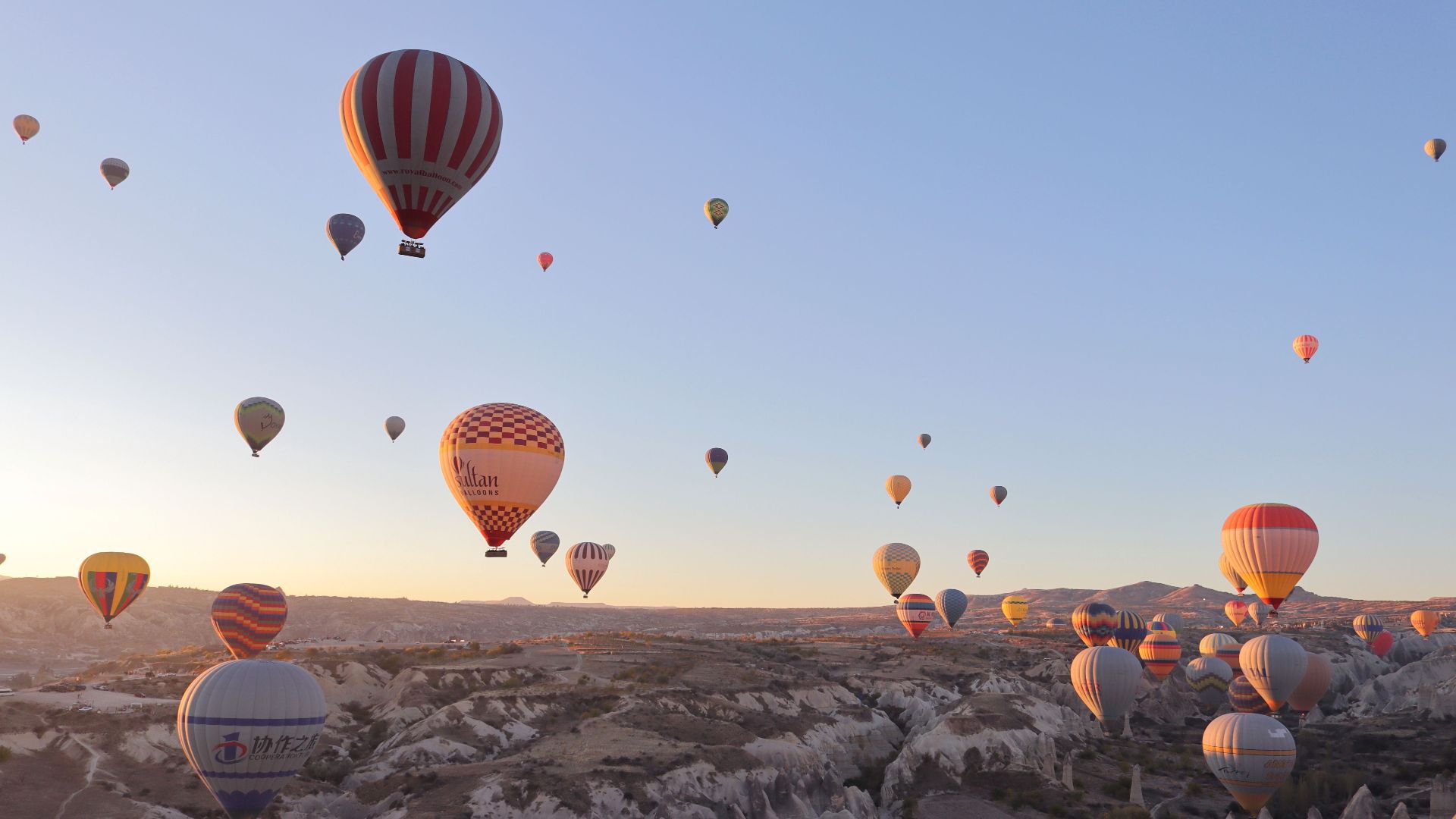 Breathtaking view of hot air balloons soaring at sunrise over Cappadocia's unique landscape in Turkey.