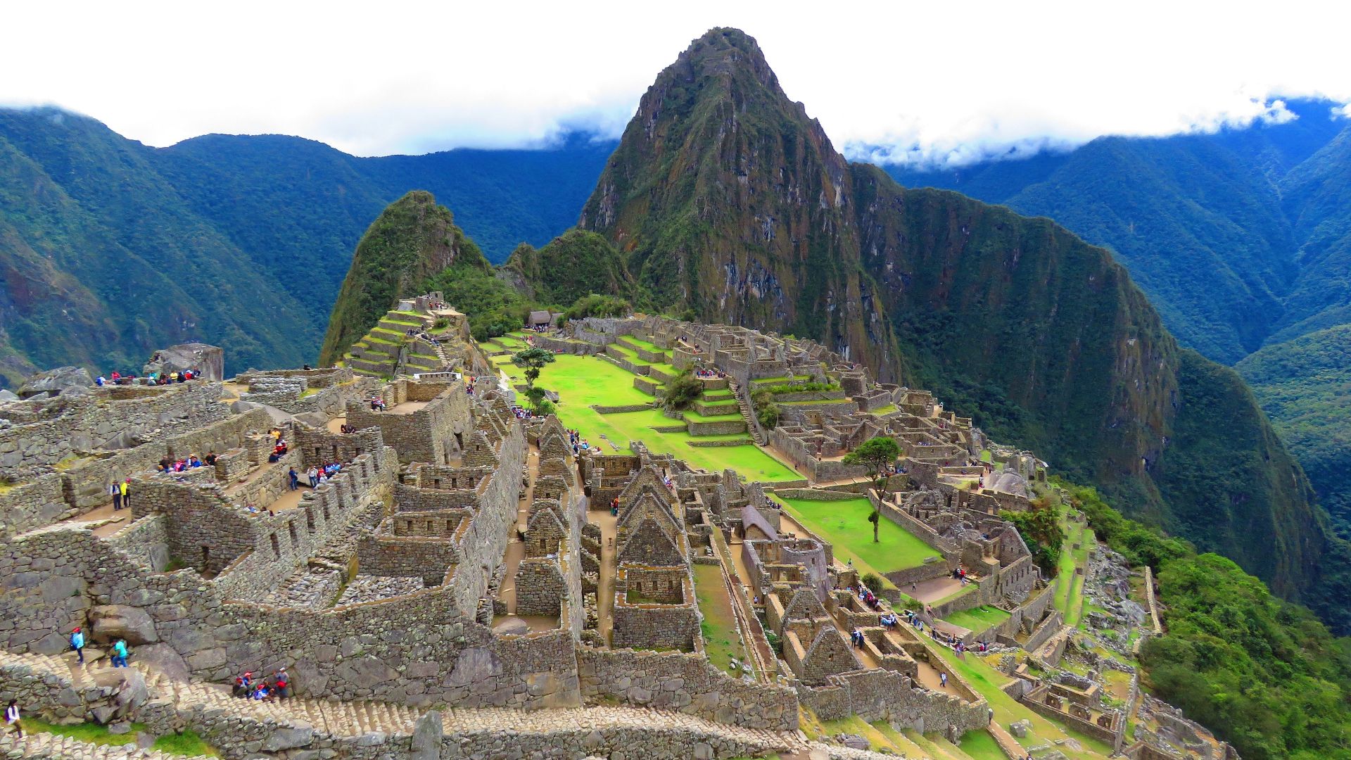 Stunning aerial perspective of Machu Picchu with lush surroundings under a cloudy sky.